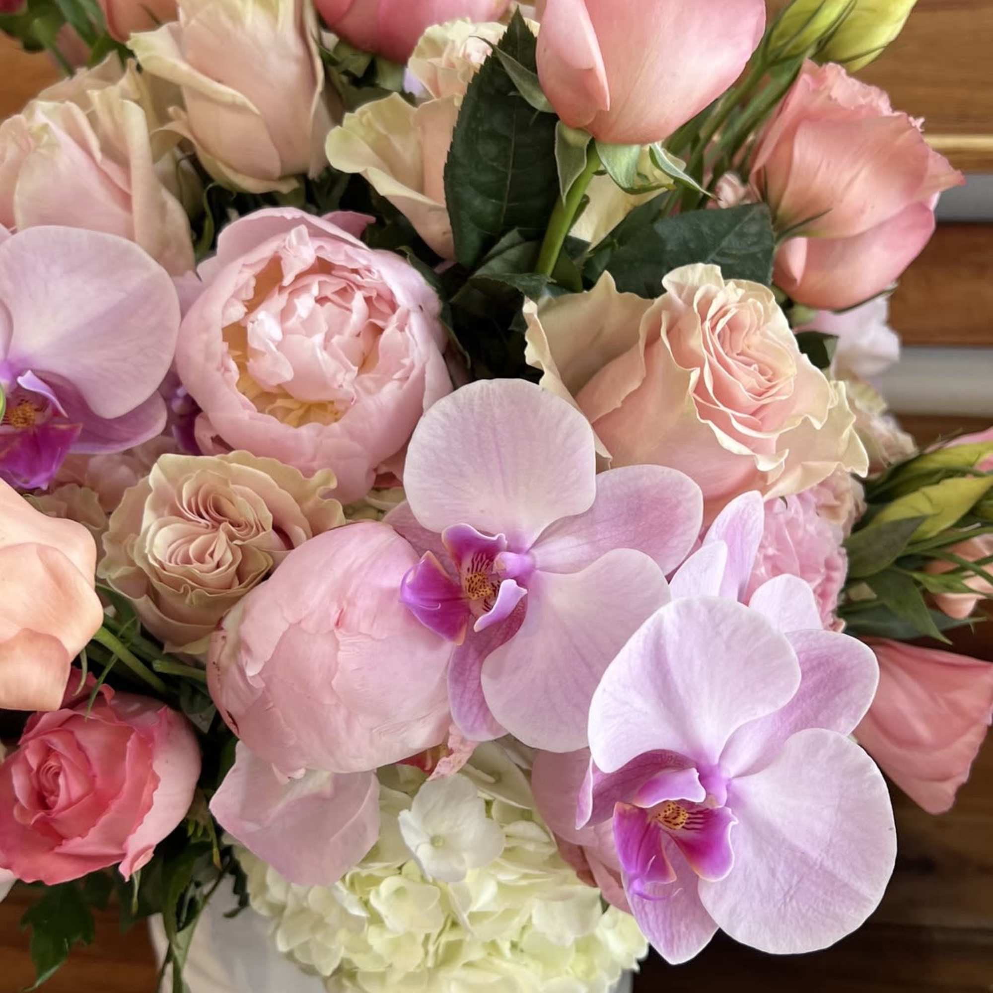 Pink and cream bouquet with orchids and roses in a white vase