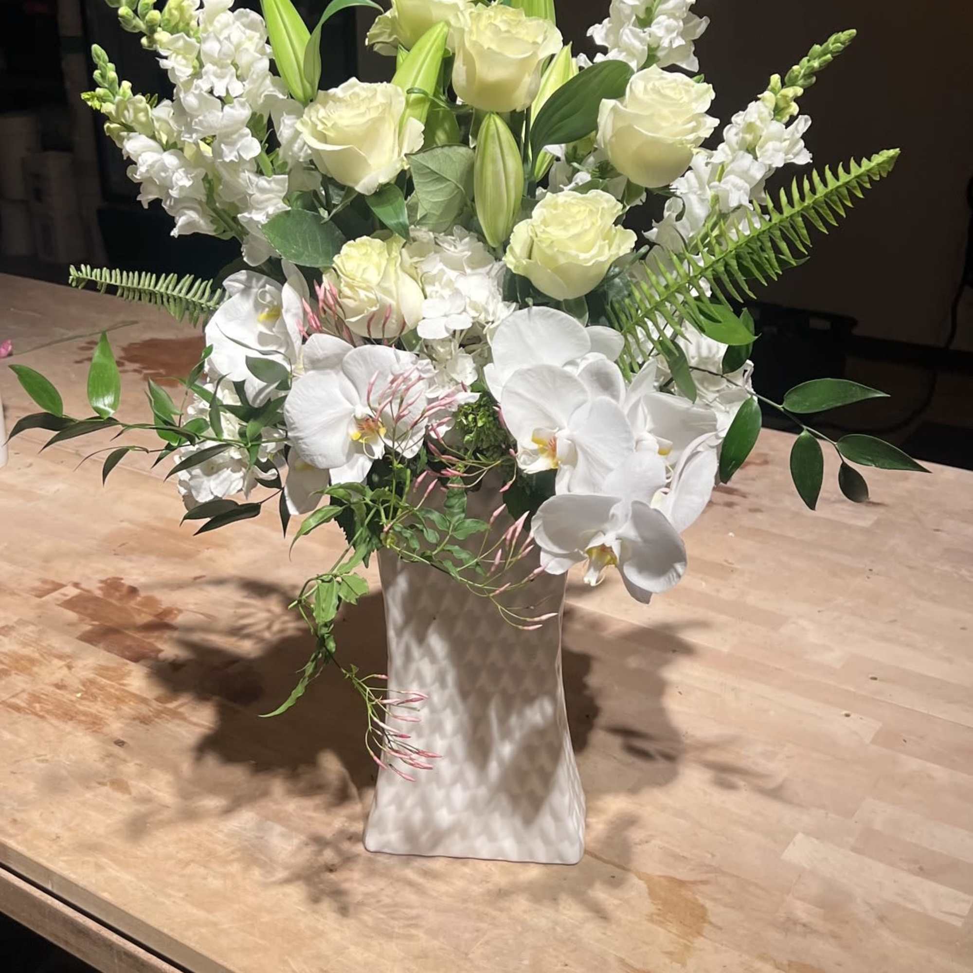 Creamy white phalaenopsis orchids and velvety white roses create a quietly elegant, photo 2 of 2