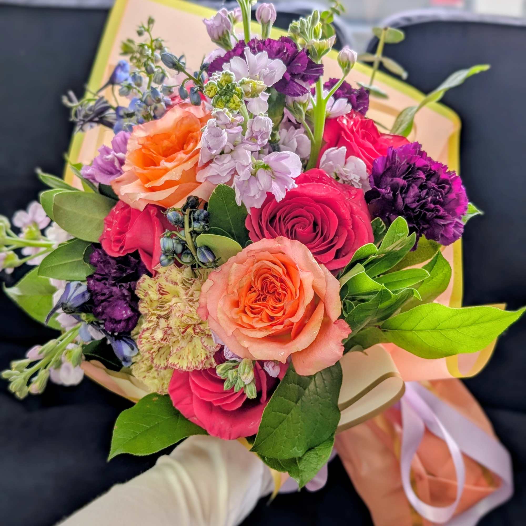 Hand-tied bouquet of pink, peach, and purple flowers with ribbon wrap