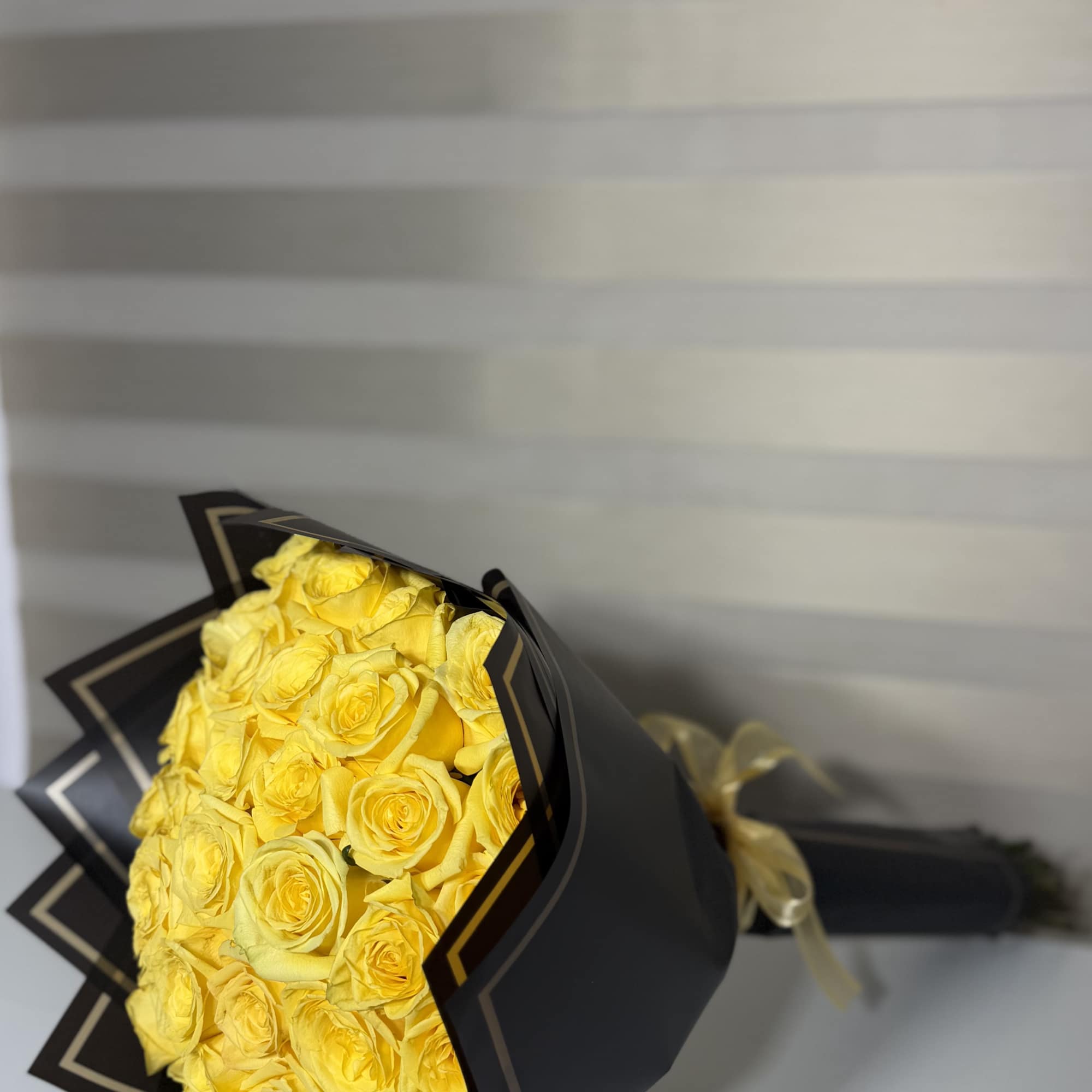Bouquet of yellow roses wrapped in black paper with a ribbon