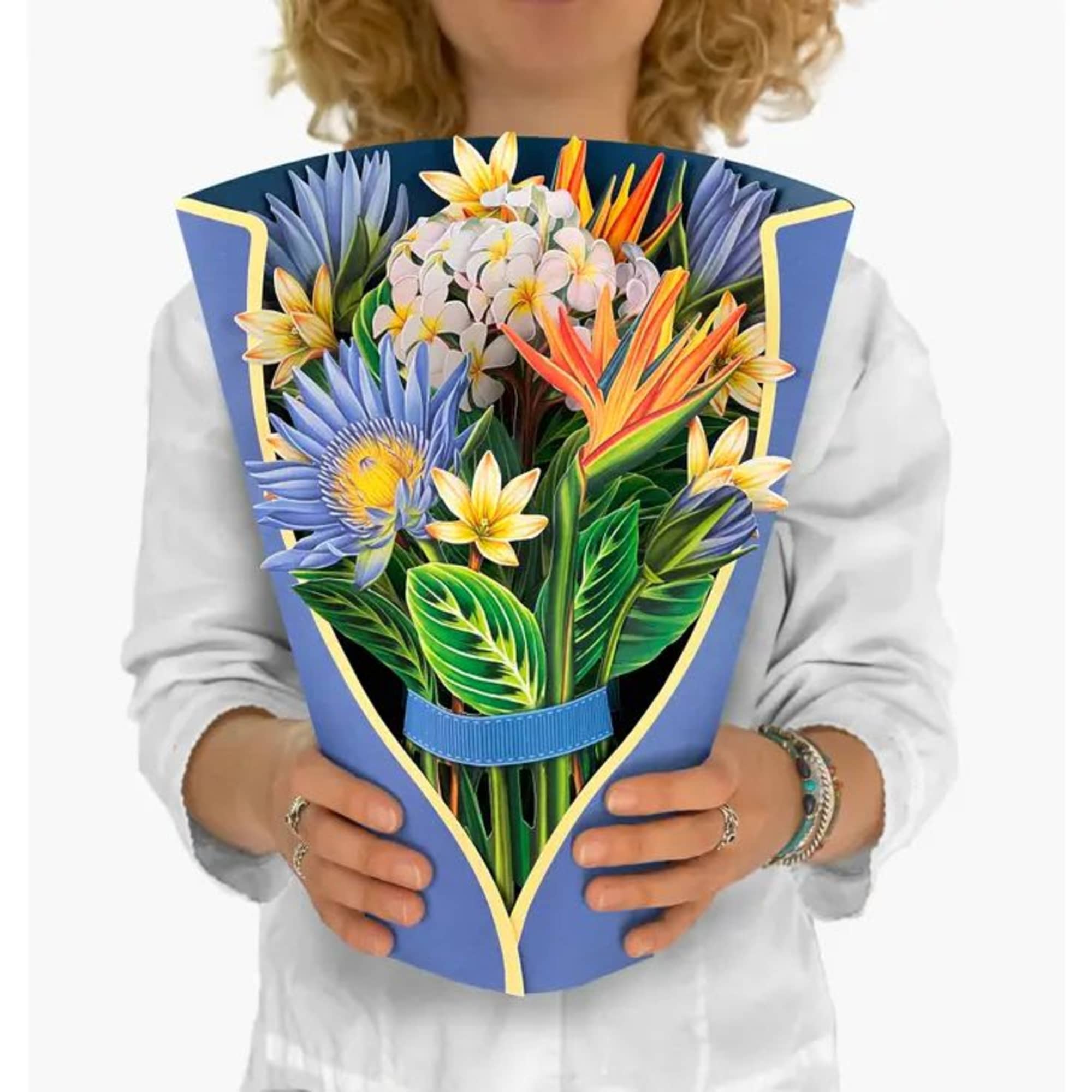 Person holding a bouquet with blue, yellow, orange, and white tropical flowers