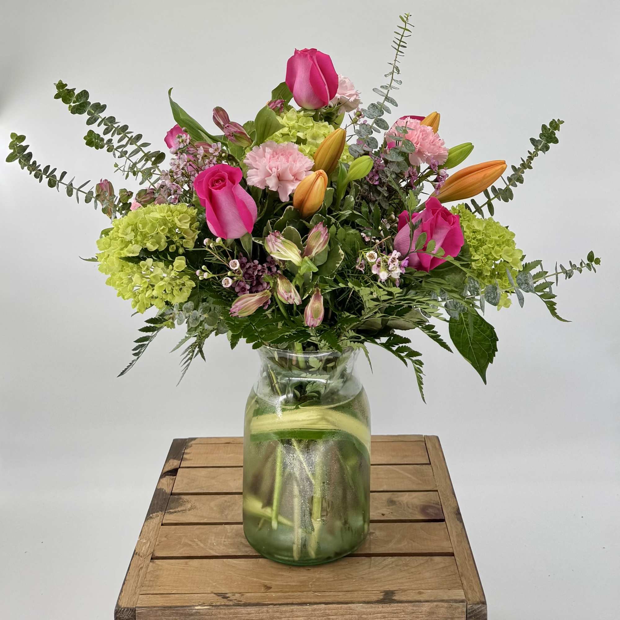 Mixed bouquet of pink roses, lilies, and hydrangeas in a glass vase