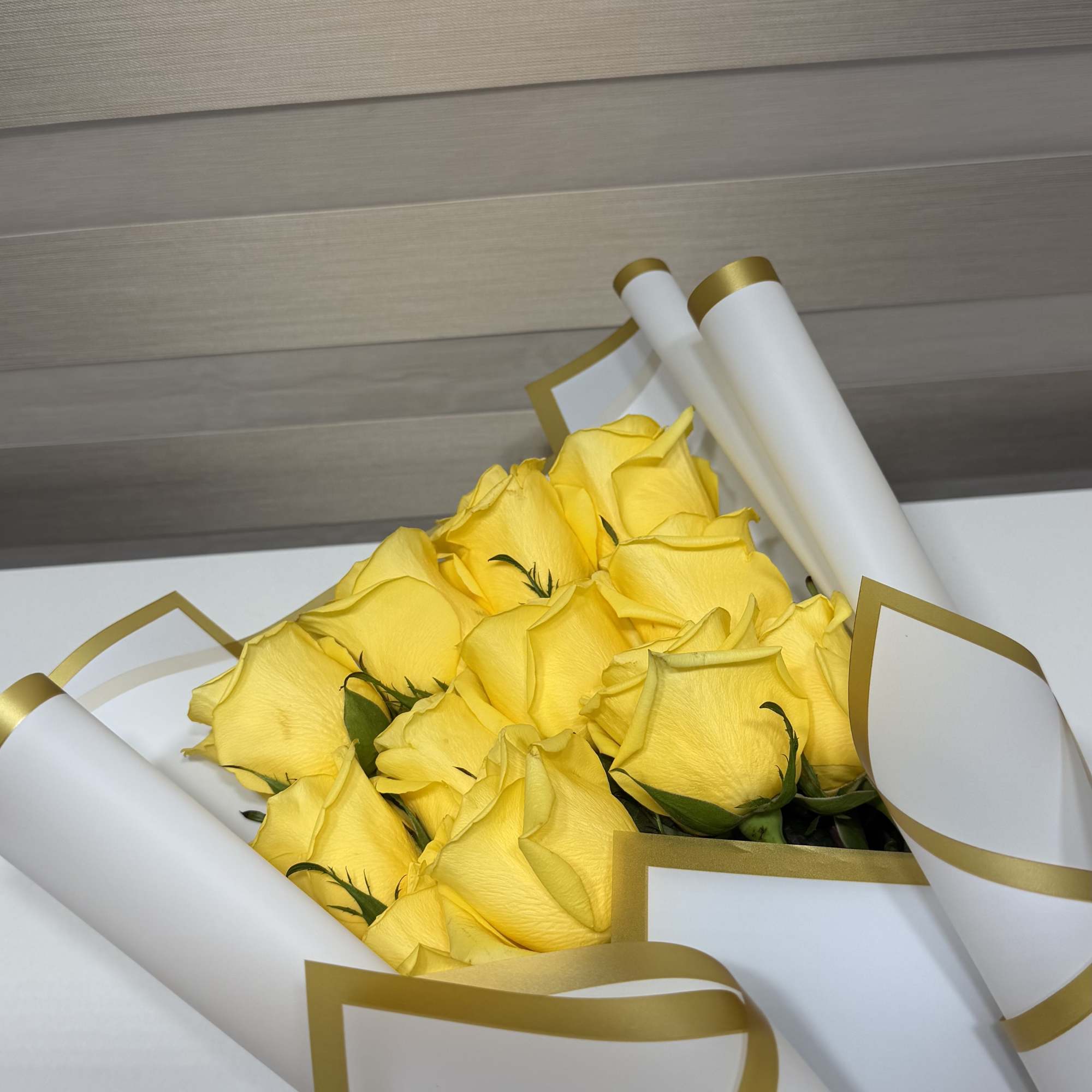 Bouquet of yellow roses wrapped in white paper with gold trim, photo 2 of 3