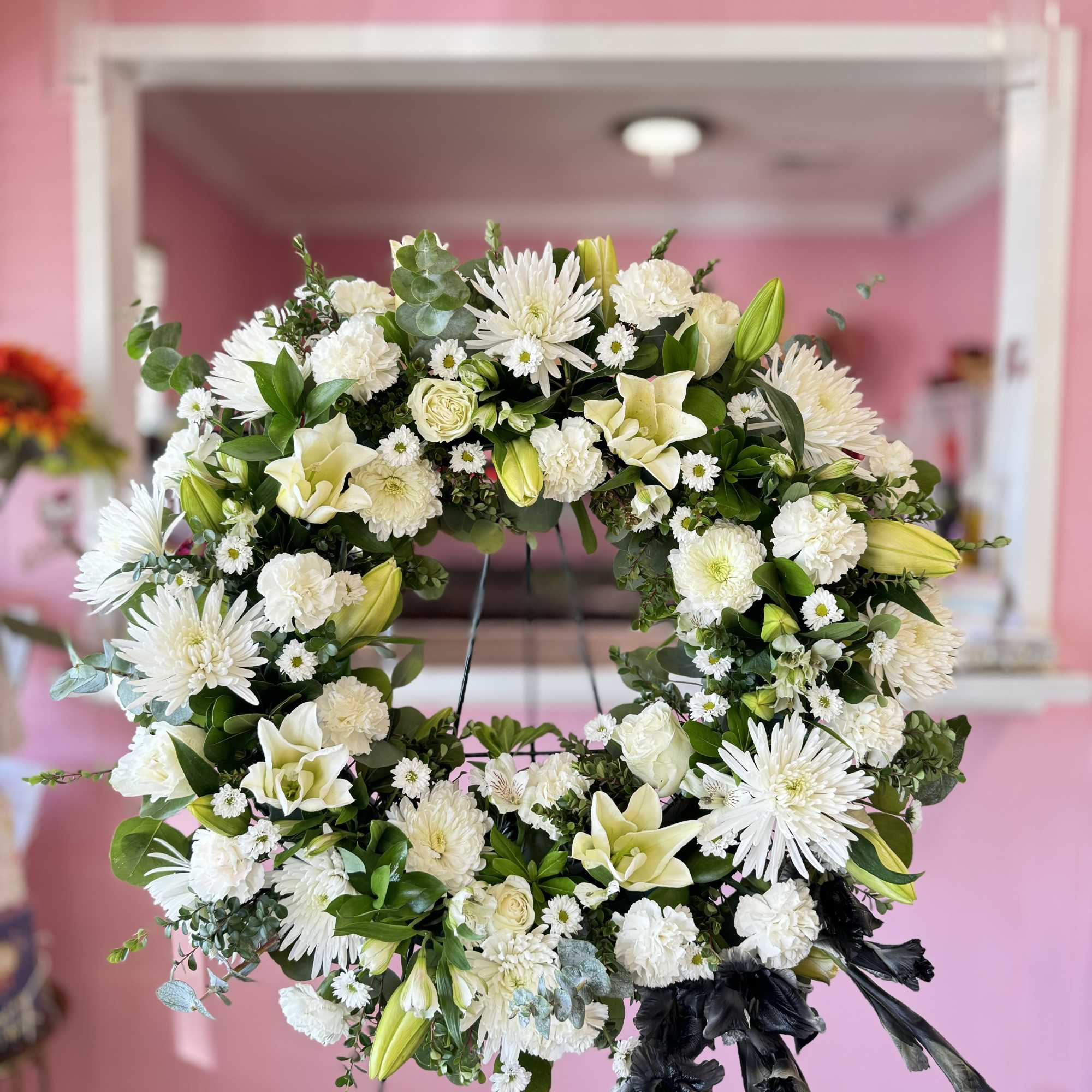 White floral wreath with lilies, chrysanthemums, and roses