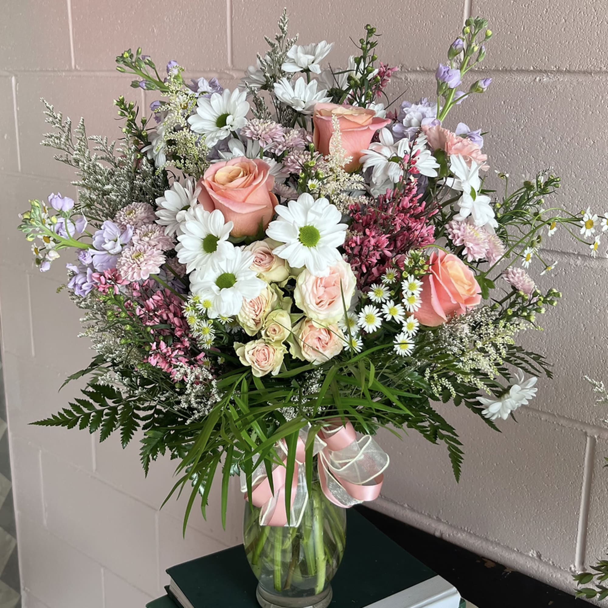 Mixed bouquet of pink roses and white daisies in a glass vase