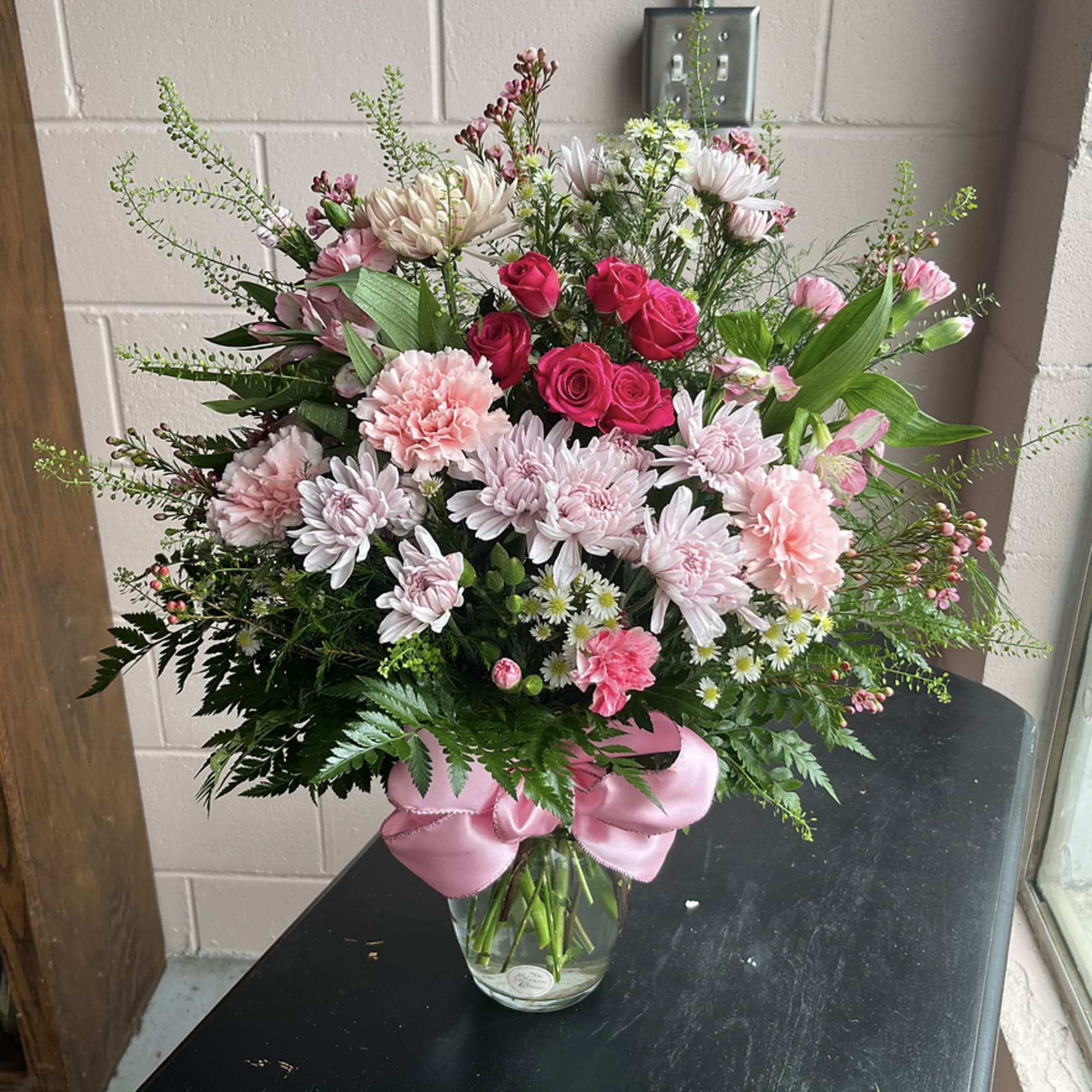Pink and white mixed bouquet in a glass vase with a pink ribbon