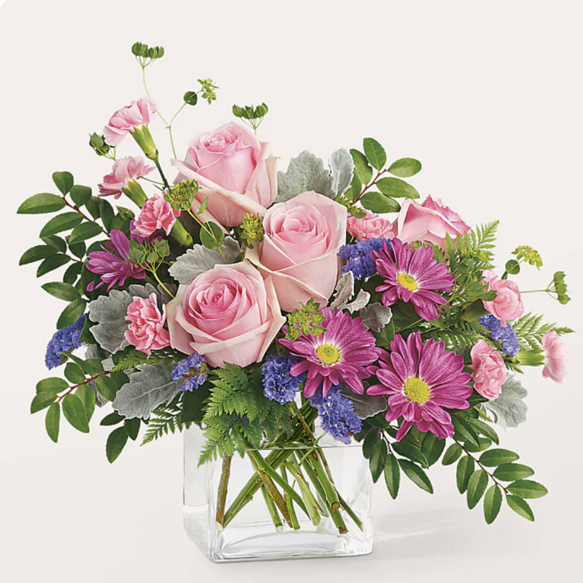 Pink roses and magenta daisies in a clear glass vase