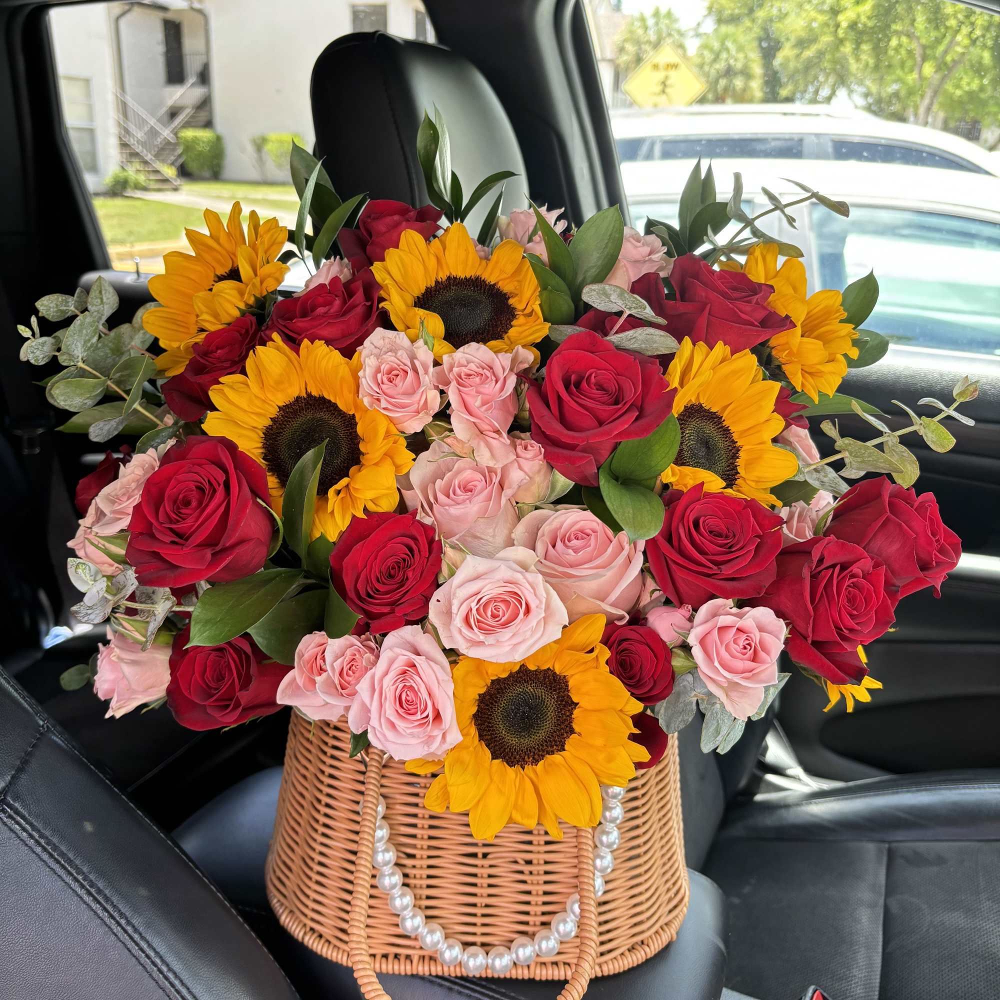 Bouquet of red and pink roses with sunflowers in a wicker basket