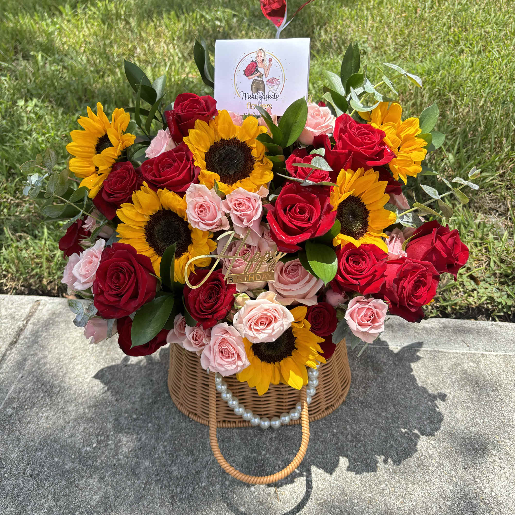 Basket arrangement of red and pink roses with sunflowers