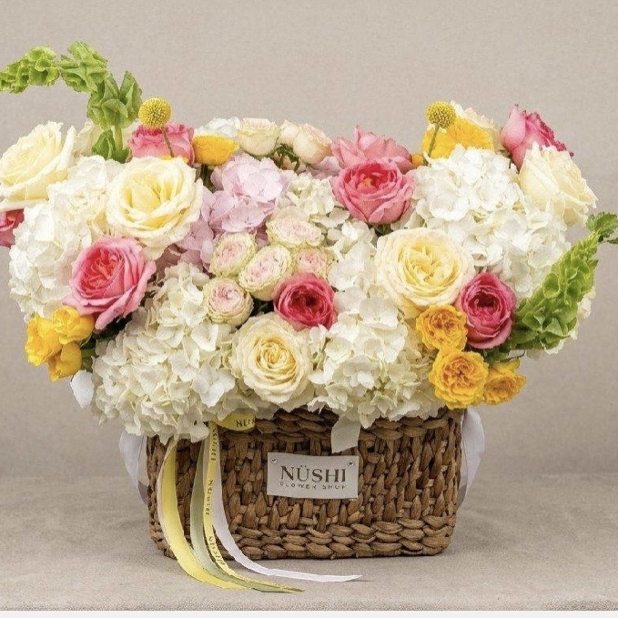 Basket arrangement of white and pink roses with yellow accents