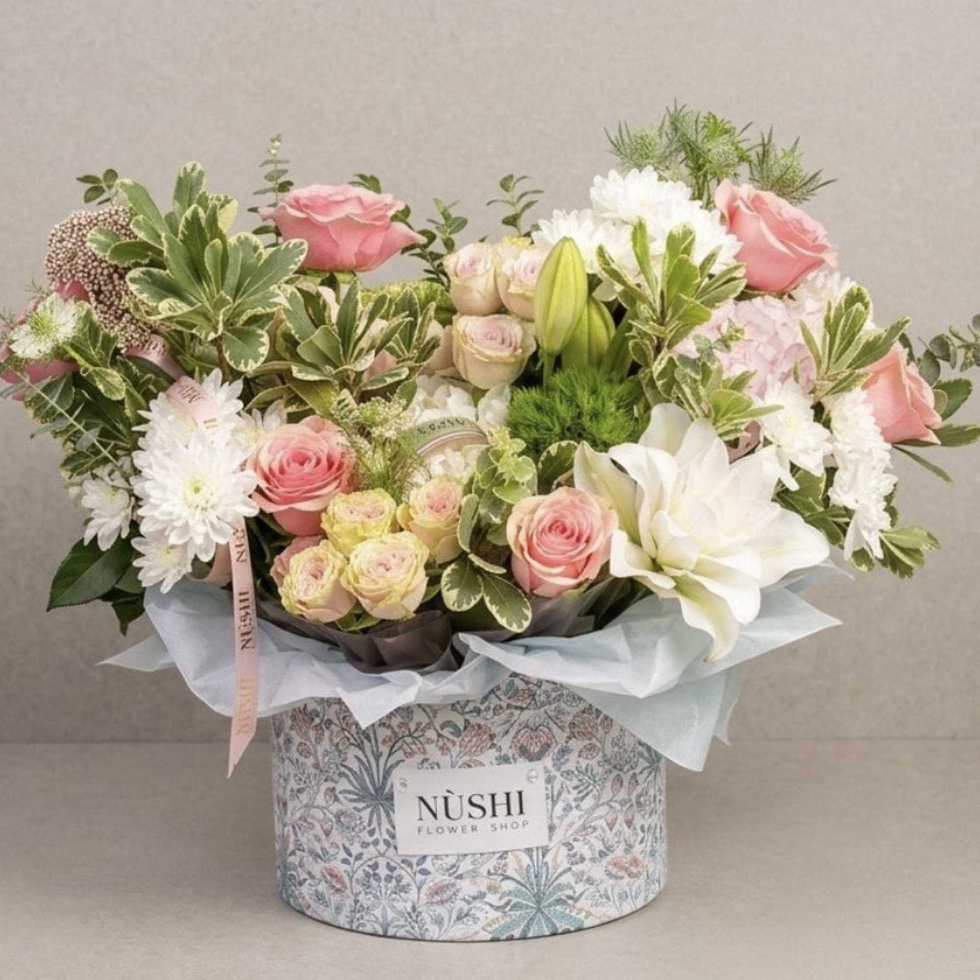 Pink and white flower arrangement in a patterned box