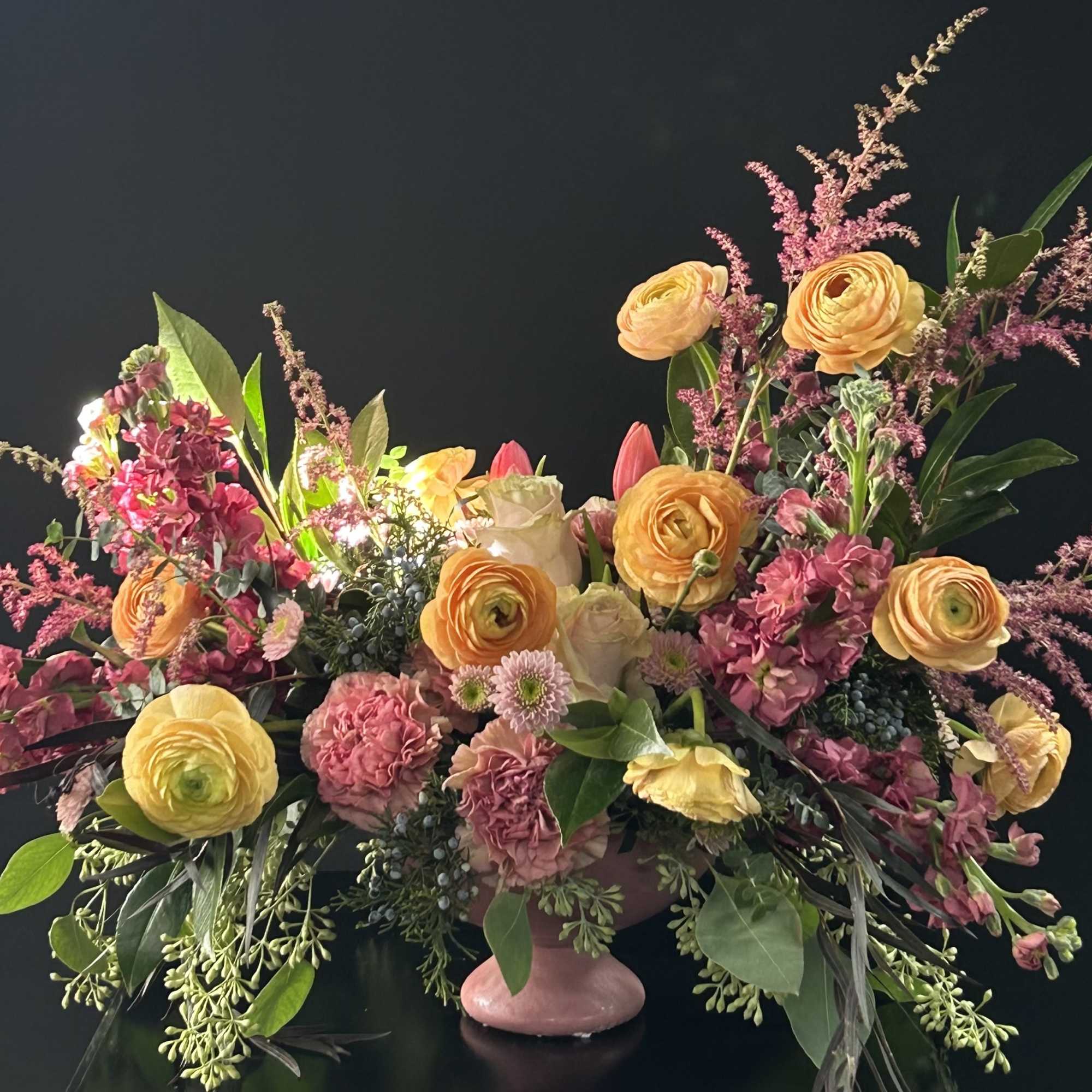 Large mixed floral arrangement in a pink pedestal vase