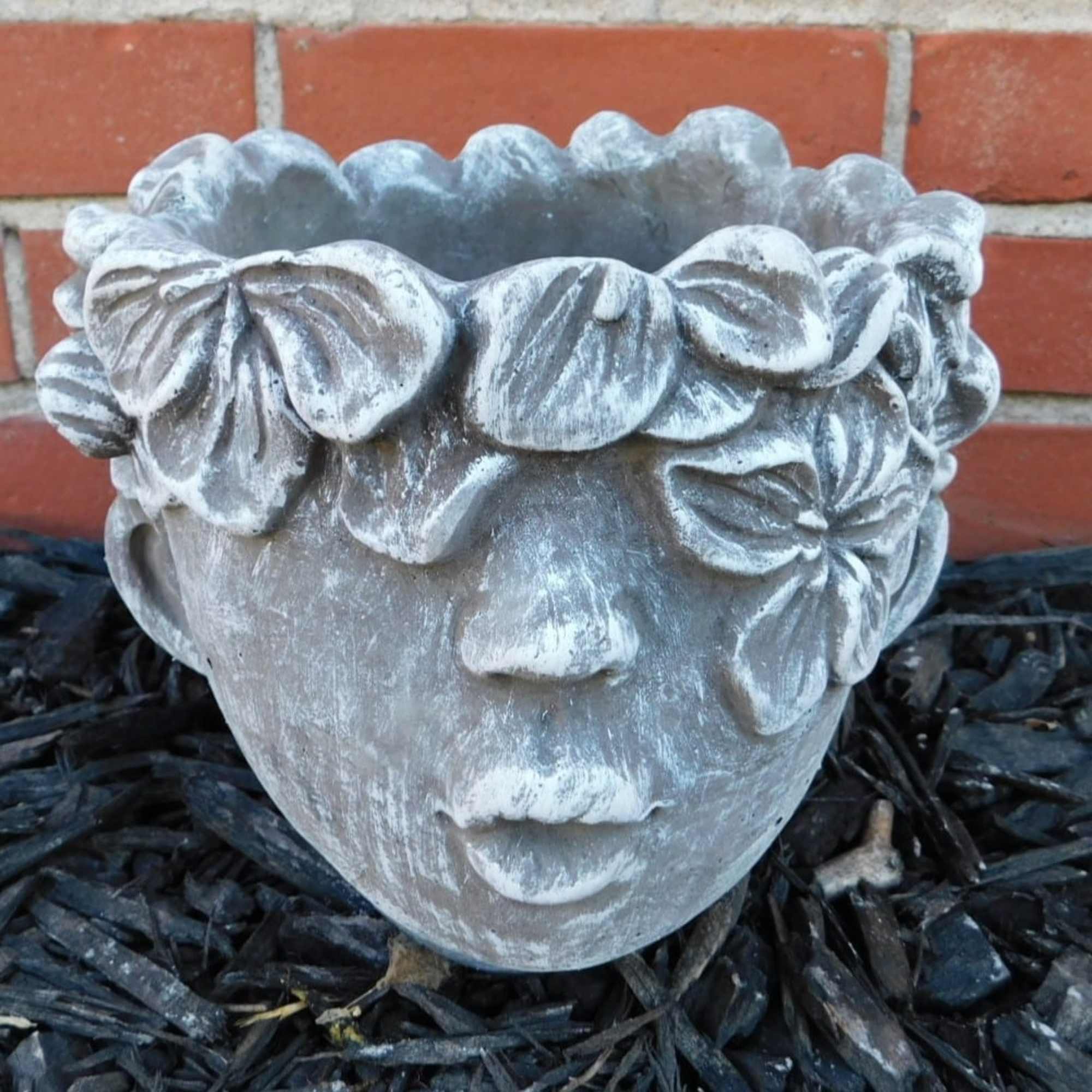 Stone face planter with floral crown detail
