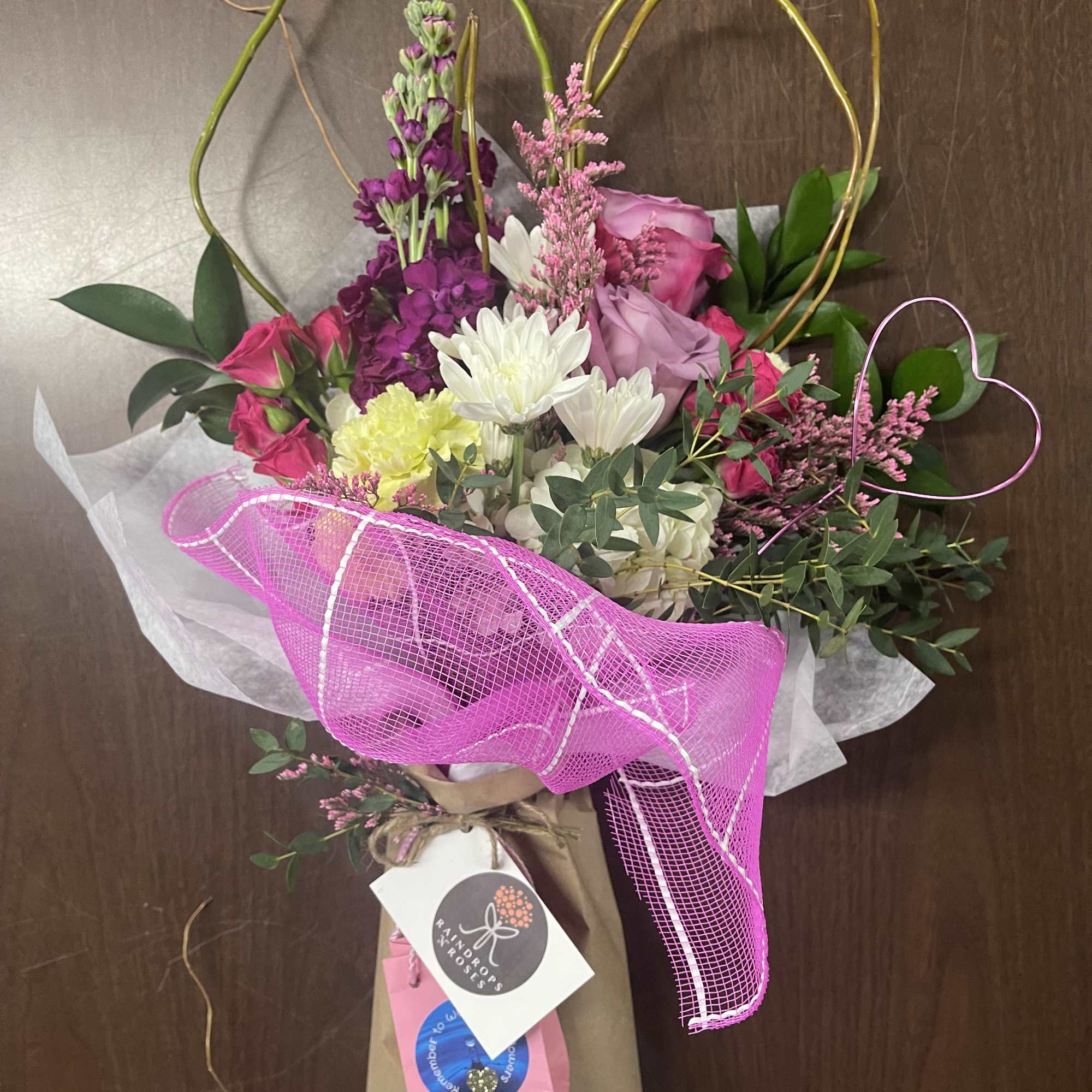 Bouquet of pink, purple, and white flowers with a bright pink ribbon wrap