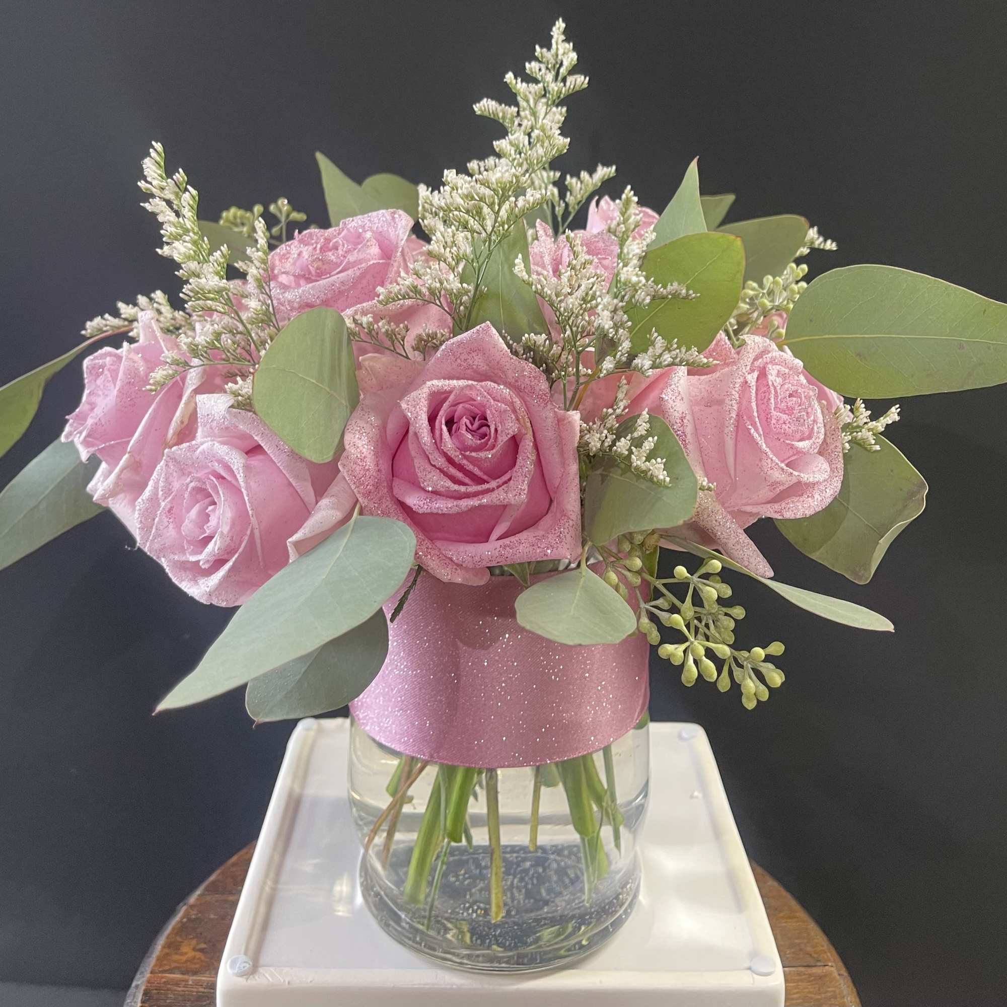 Pink roses in a clear glass vase with eucalyptus and filler flowers