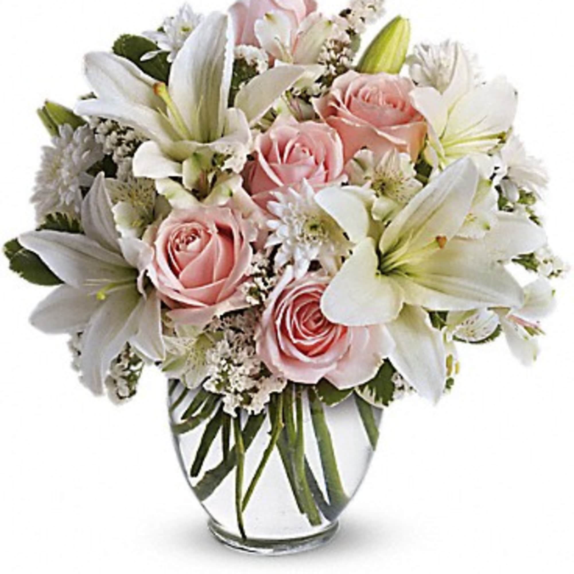 Pink roses and white lilies arranged in a clear glass vase