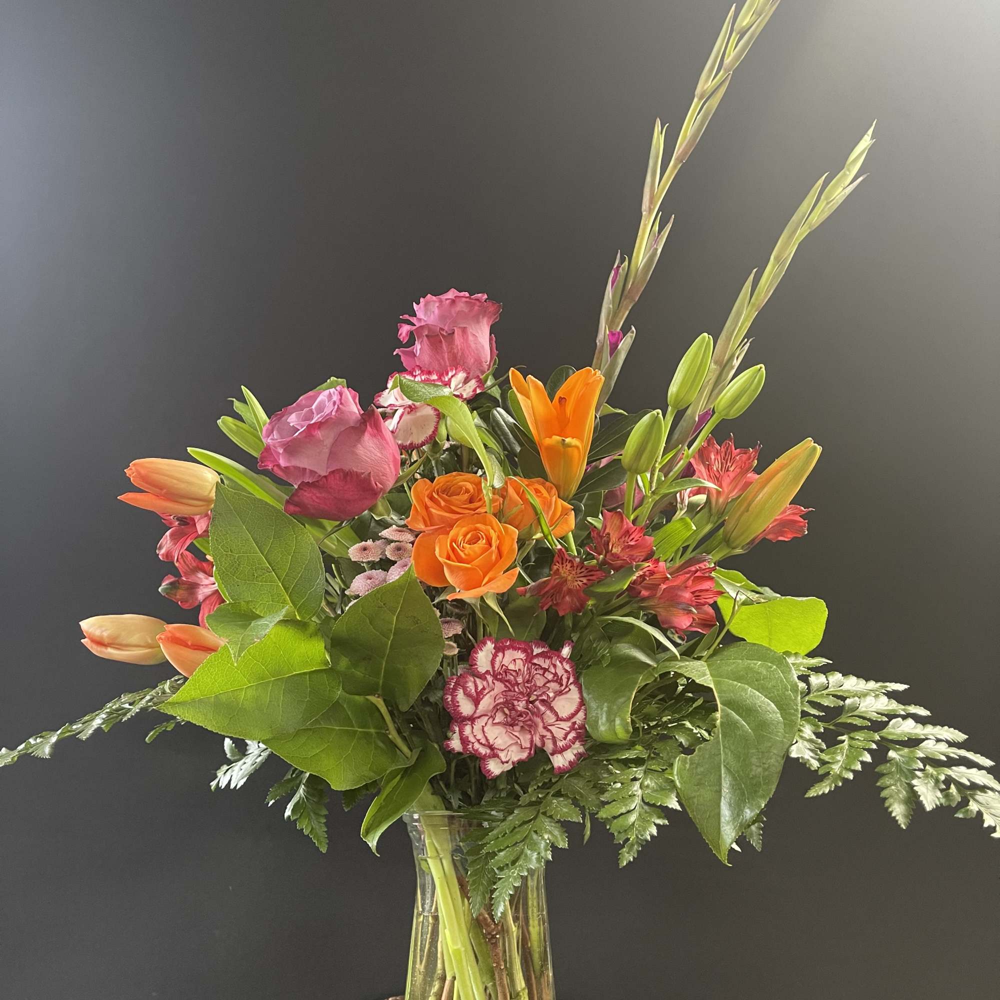 Mixed bouquet of orange and pink flowers in a clear glass vase