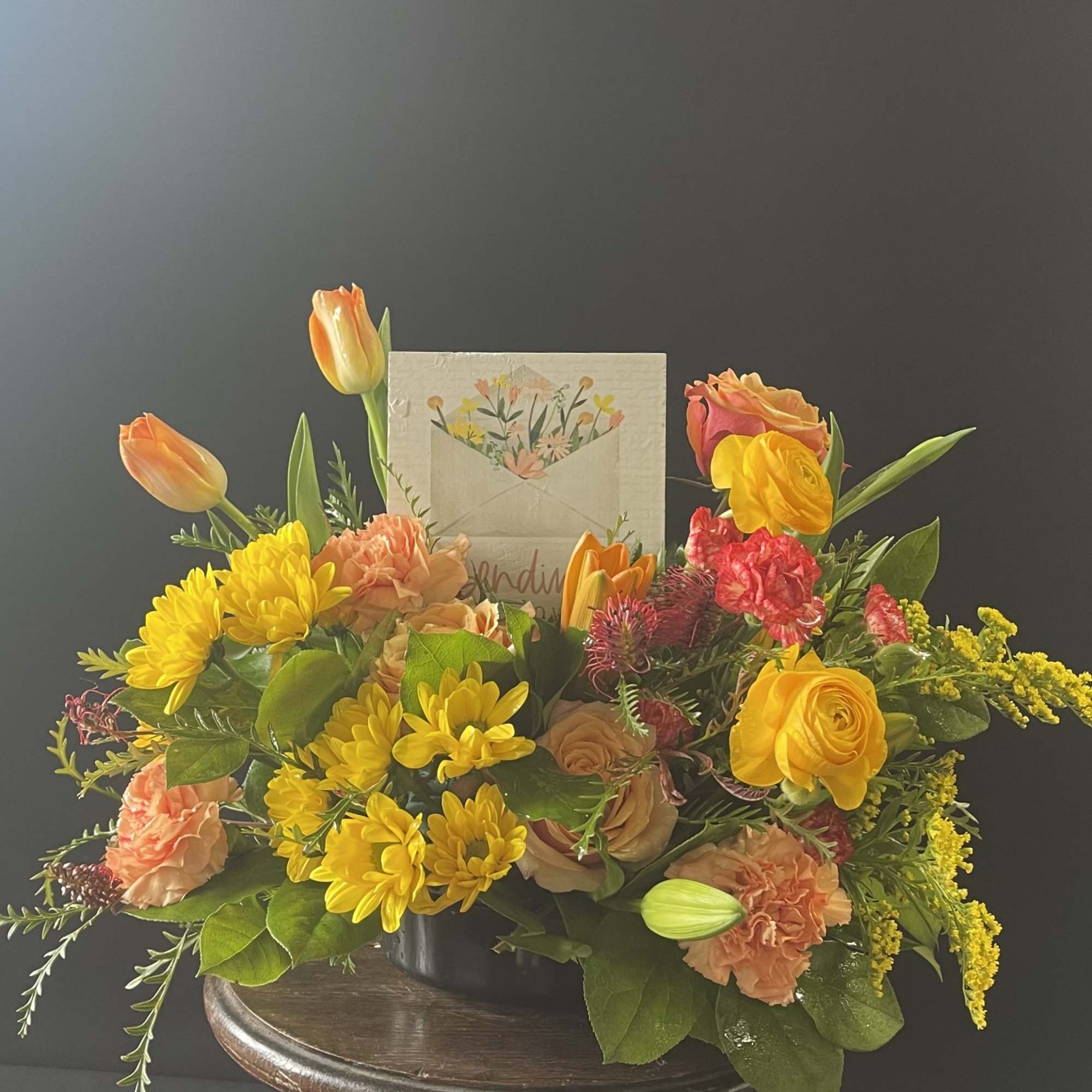Mixed bouquet in a low container with yellow, orange, and pink flowers
