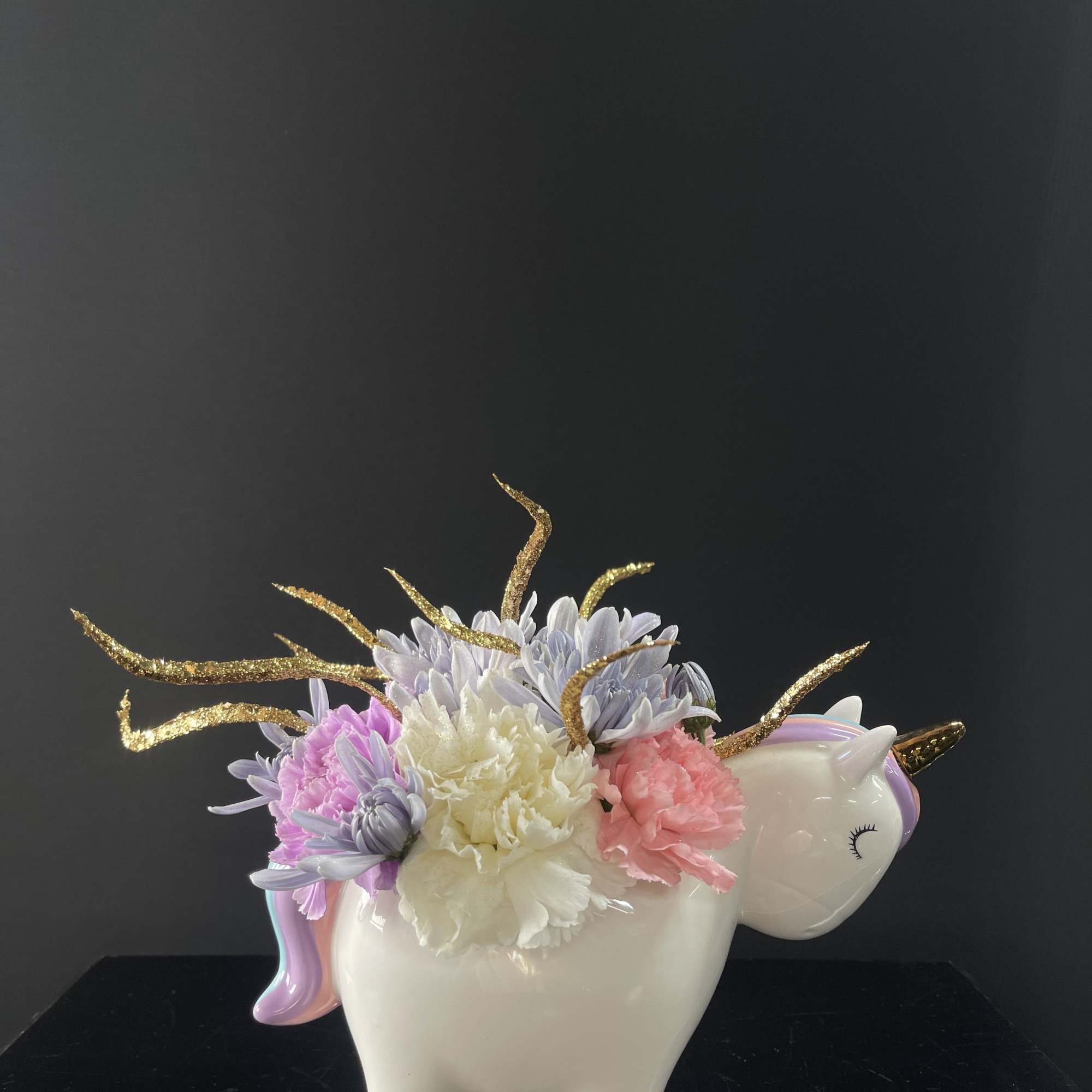 Unicorn-shaped vase with pastel flowers and gold glitter accents