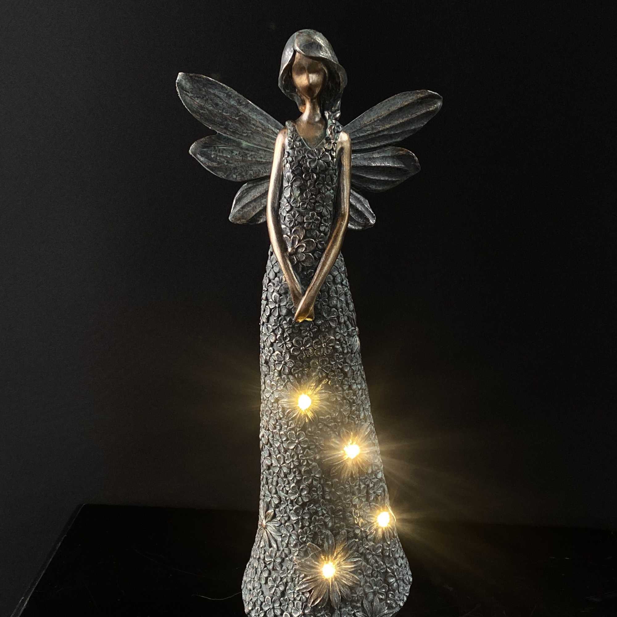 Decorative angel figurine with glowing lights on a dark background
