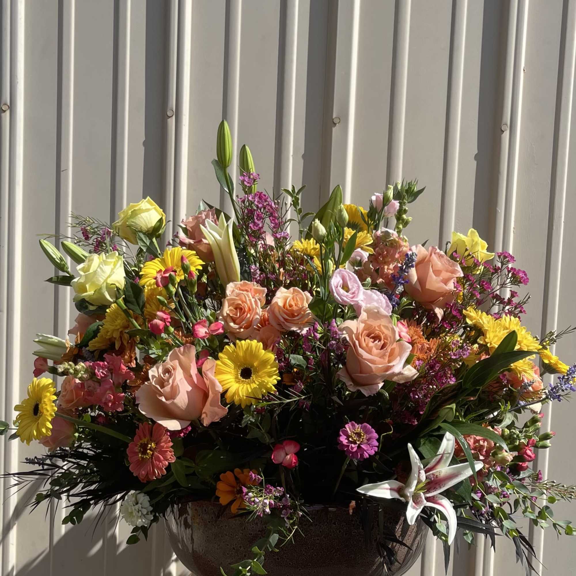 Large mixed bouquet in a dark bowl vase with pink, yellow, and white blooms