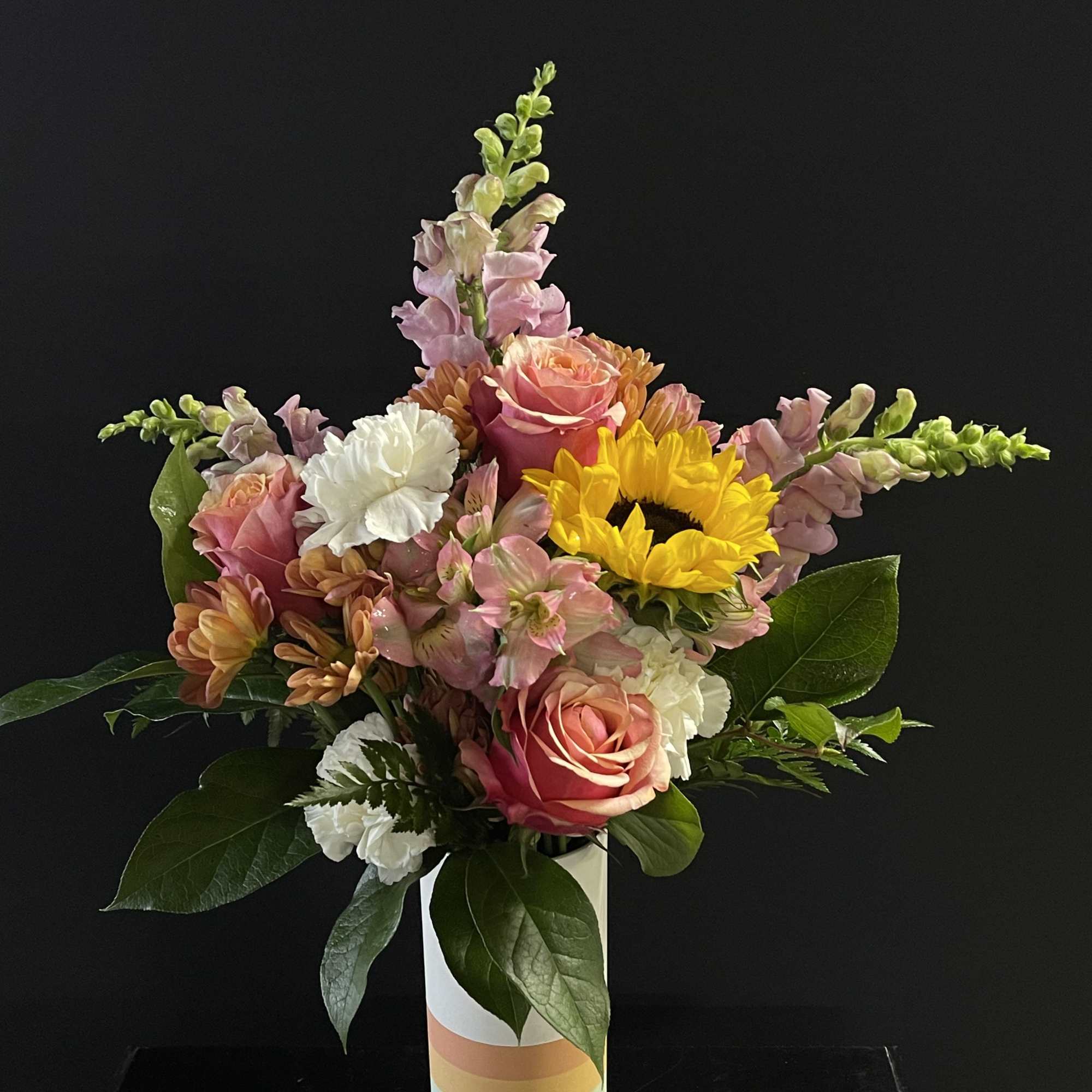Mixed bouquet of pink, white, and yellow flowers in a striped vase