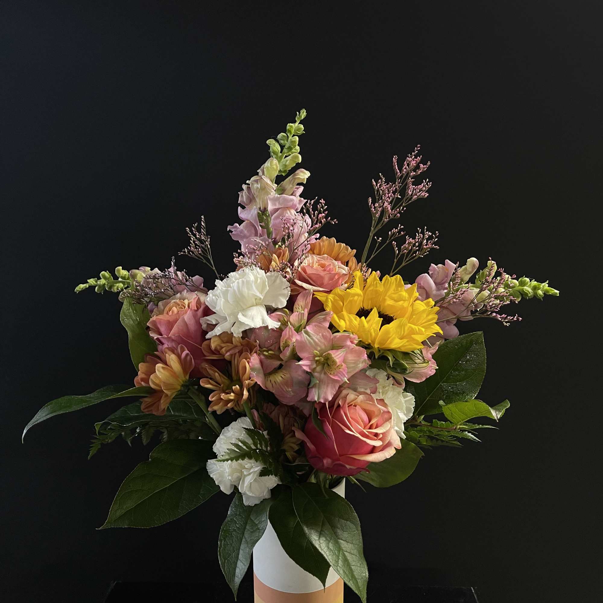 Mixed bouquet of pink, white, and yellow flowers in a striped vase