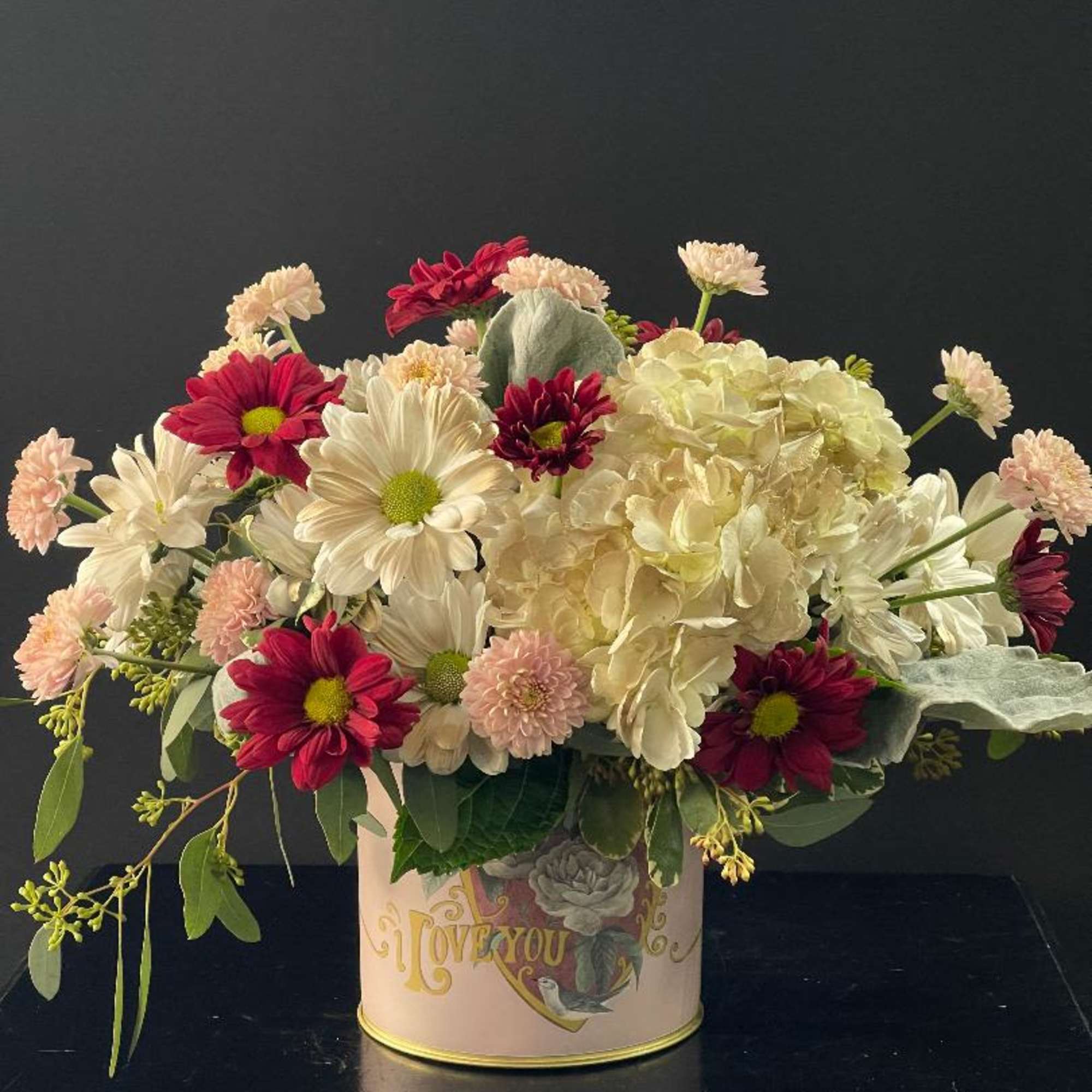 Mixed bouquet of white and red flowers in a decorative tin container