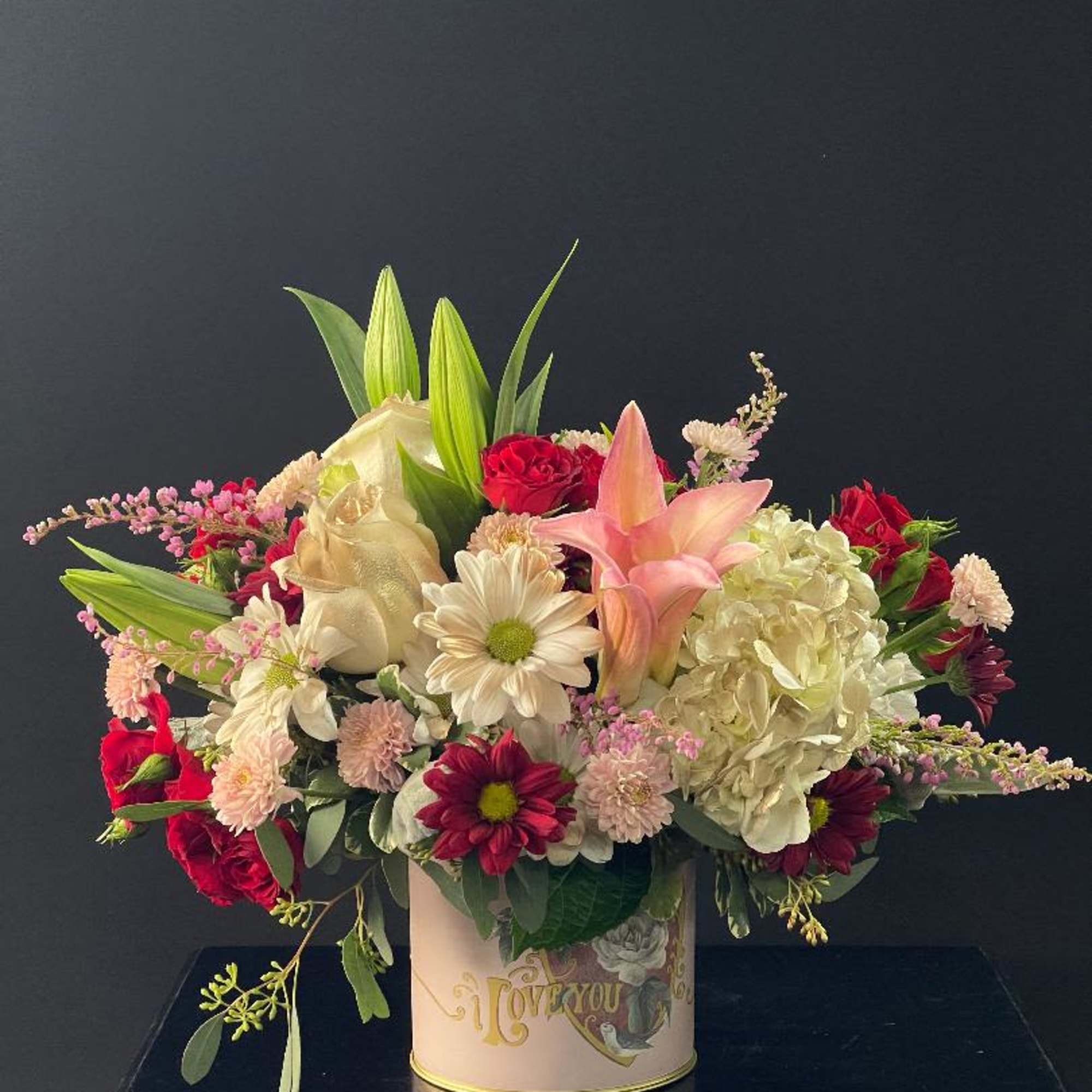 Mixed bouquet in a decorative tin container with pink and white flowers