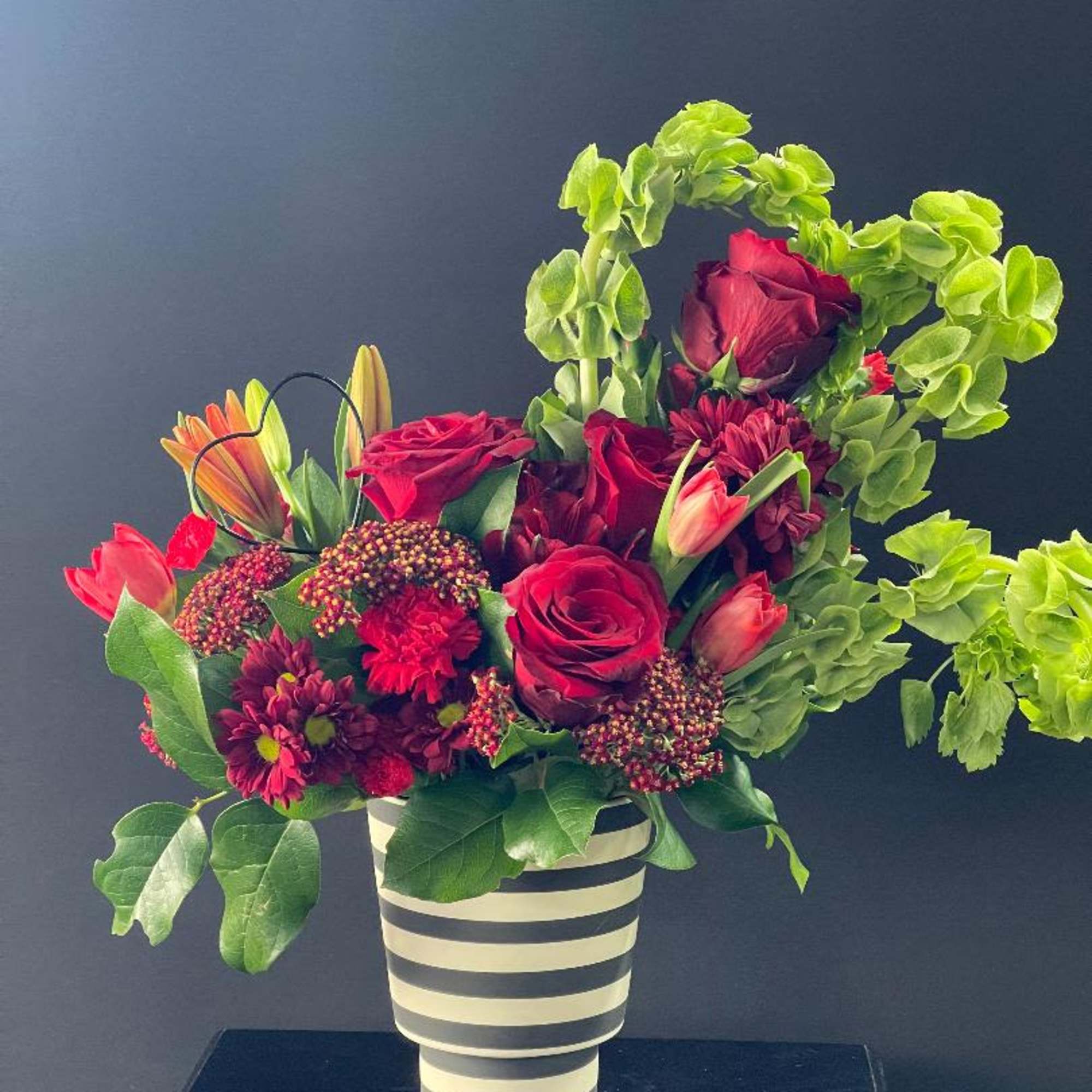 Red roses and mixed blooms in a striped vase