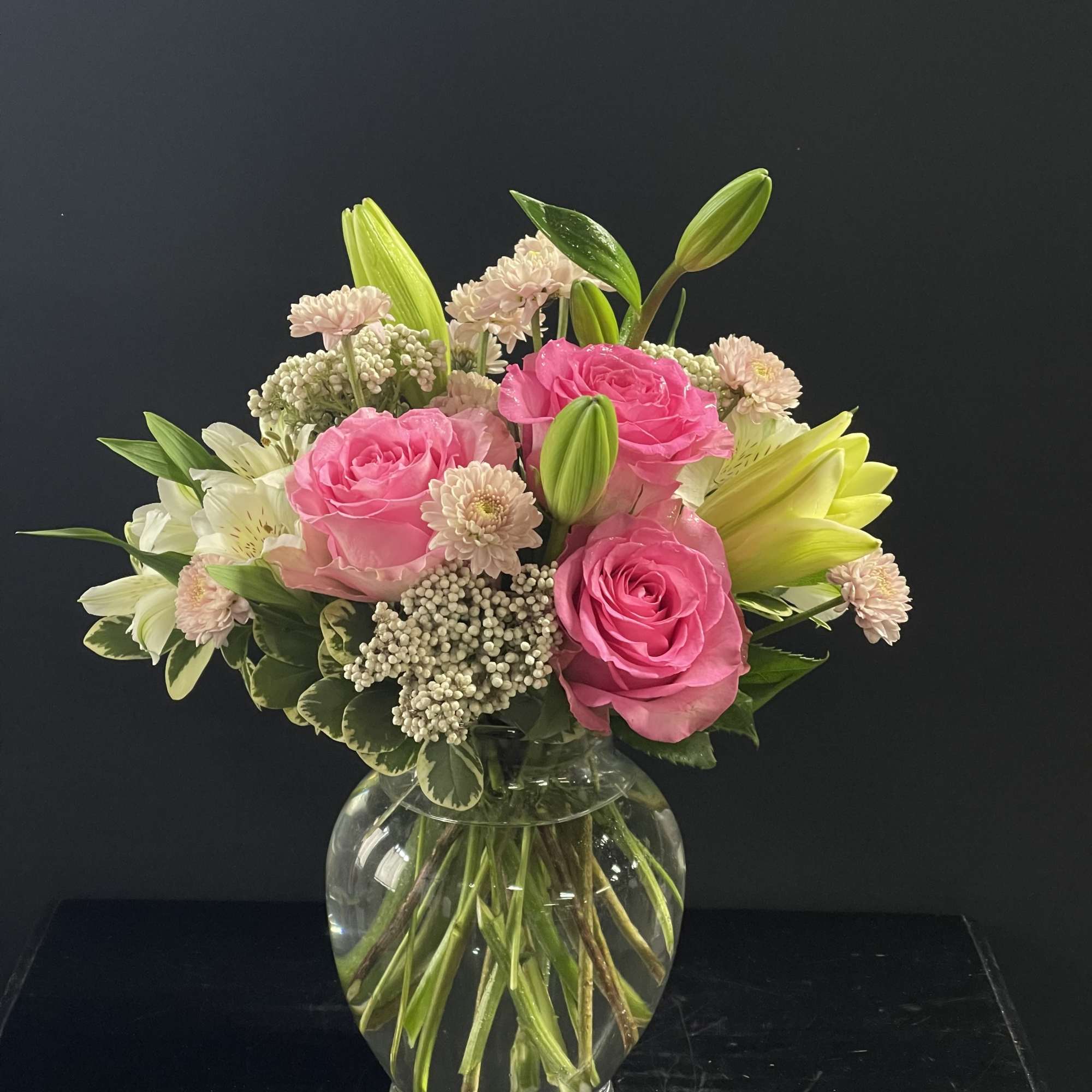 Pink roses and white lilies arranged in a clear glass vase