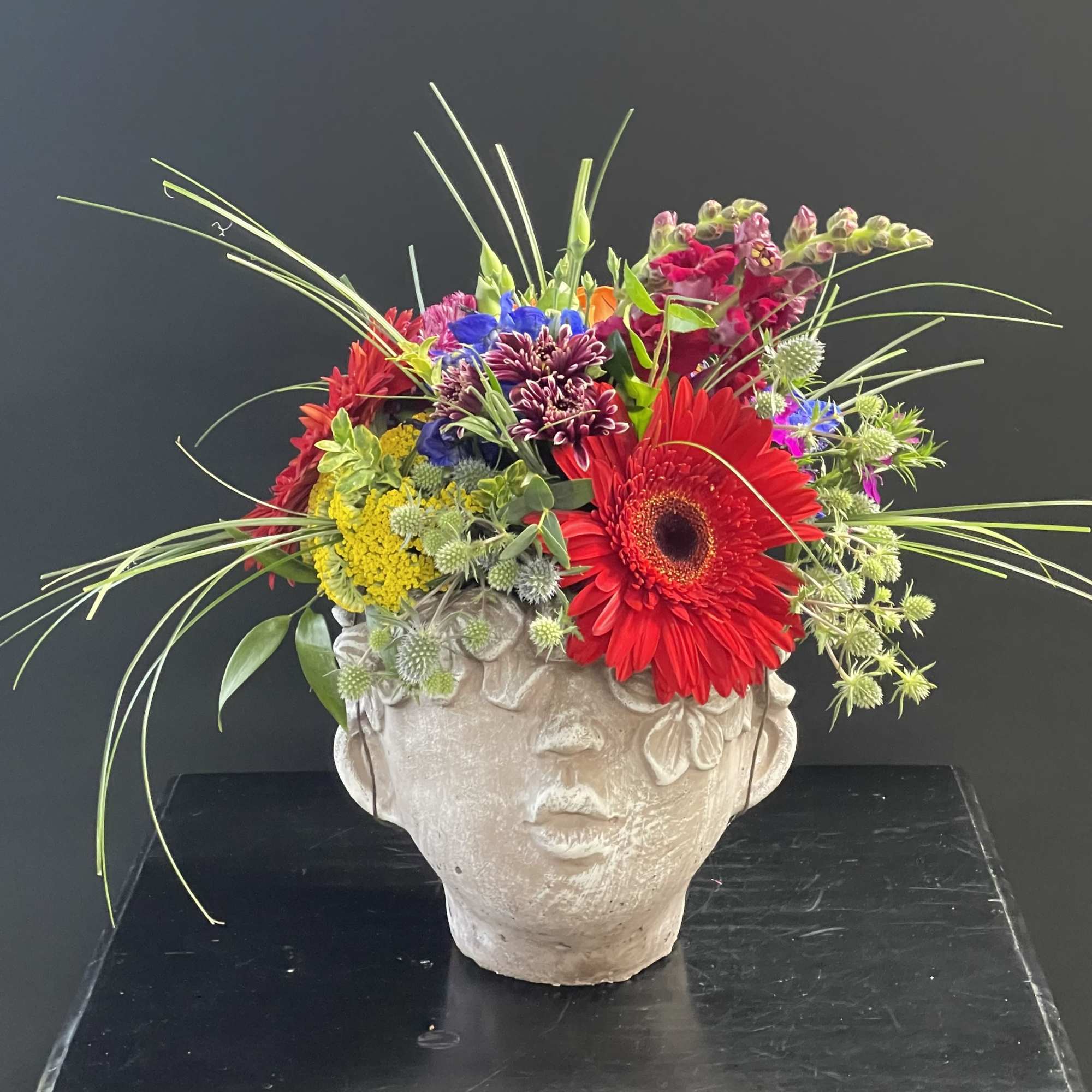 Colorful mixed flower arrangement in a sculpted face planter