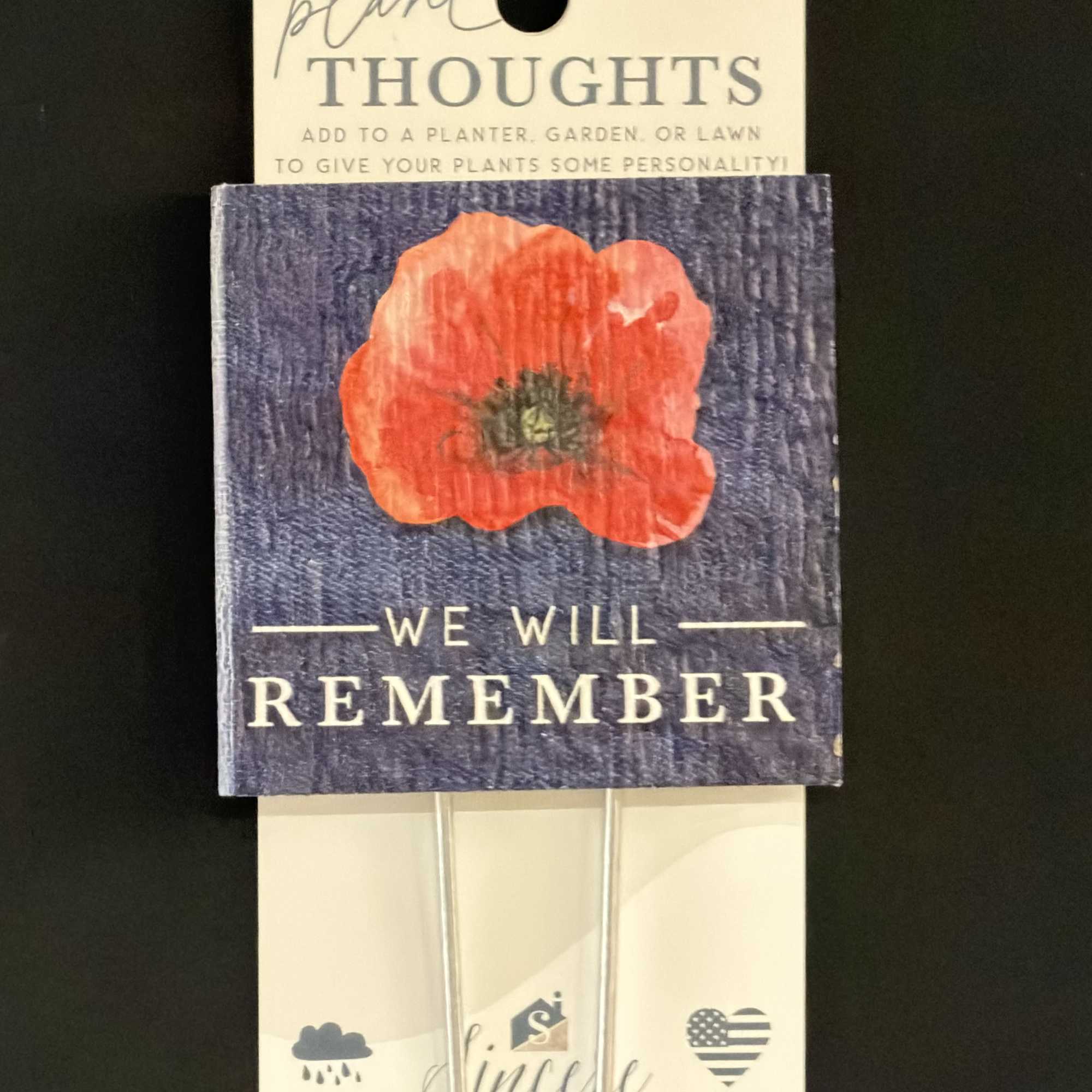 Memorial plant stake with a red poppy and the words We Will Remember
