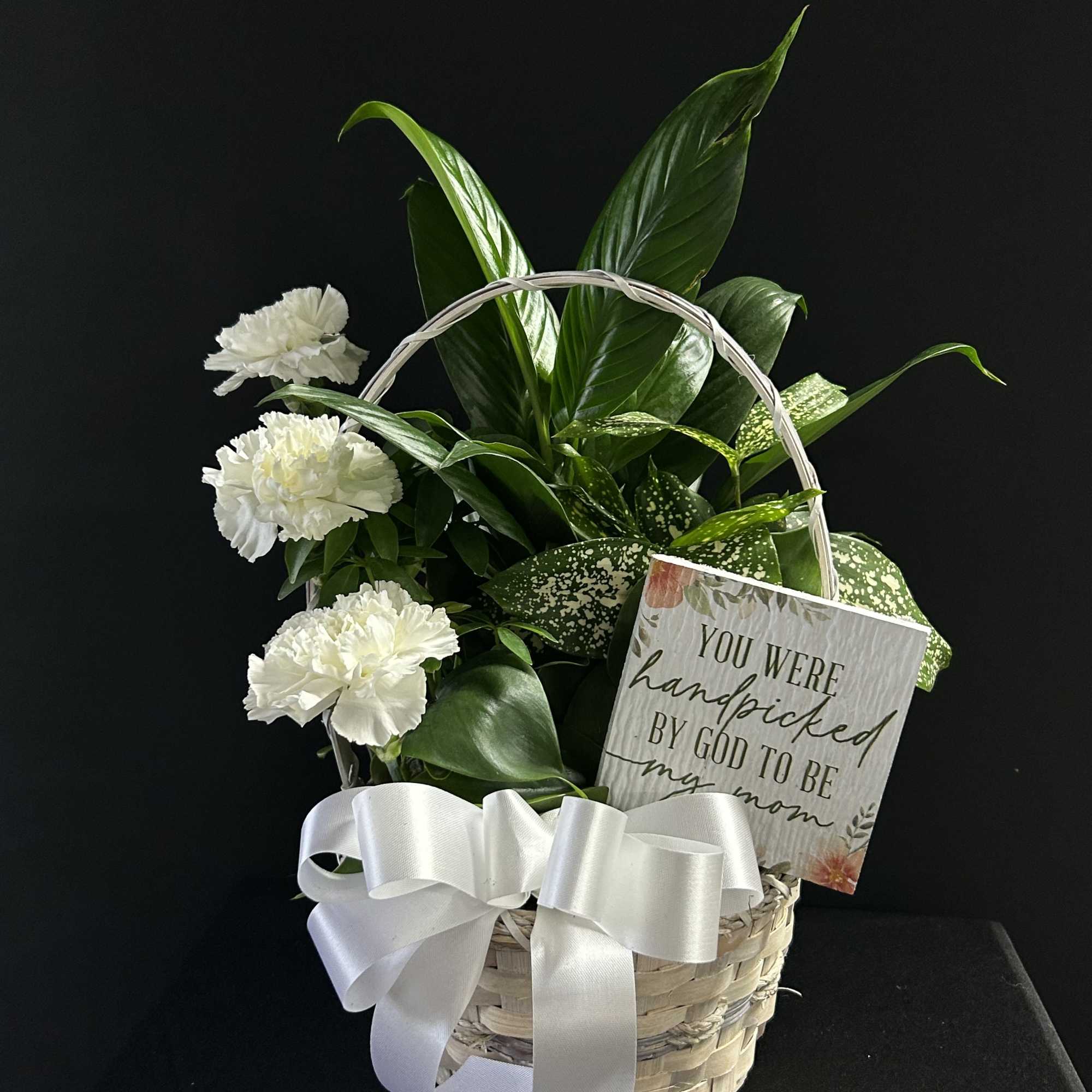 White carnations in a wicker basket with a ribbon and card