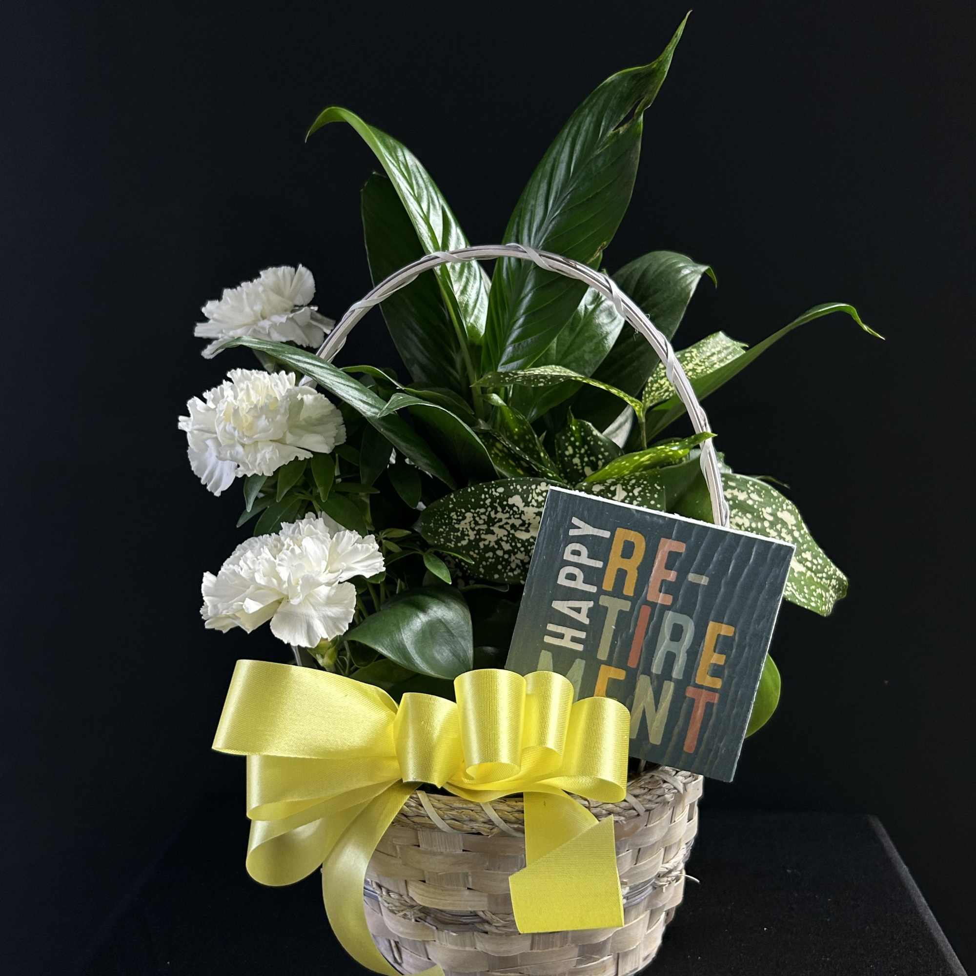 White carnations in a wicker basket with a yellow ribbon and retirement card