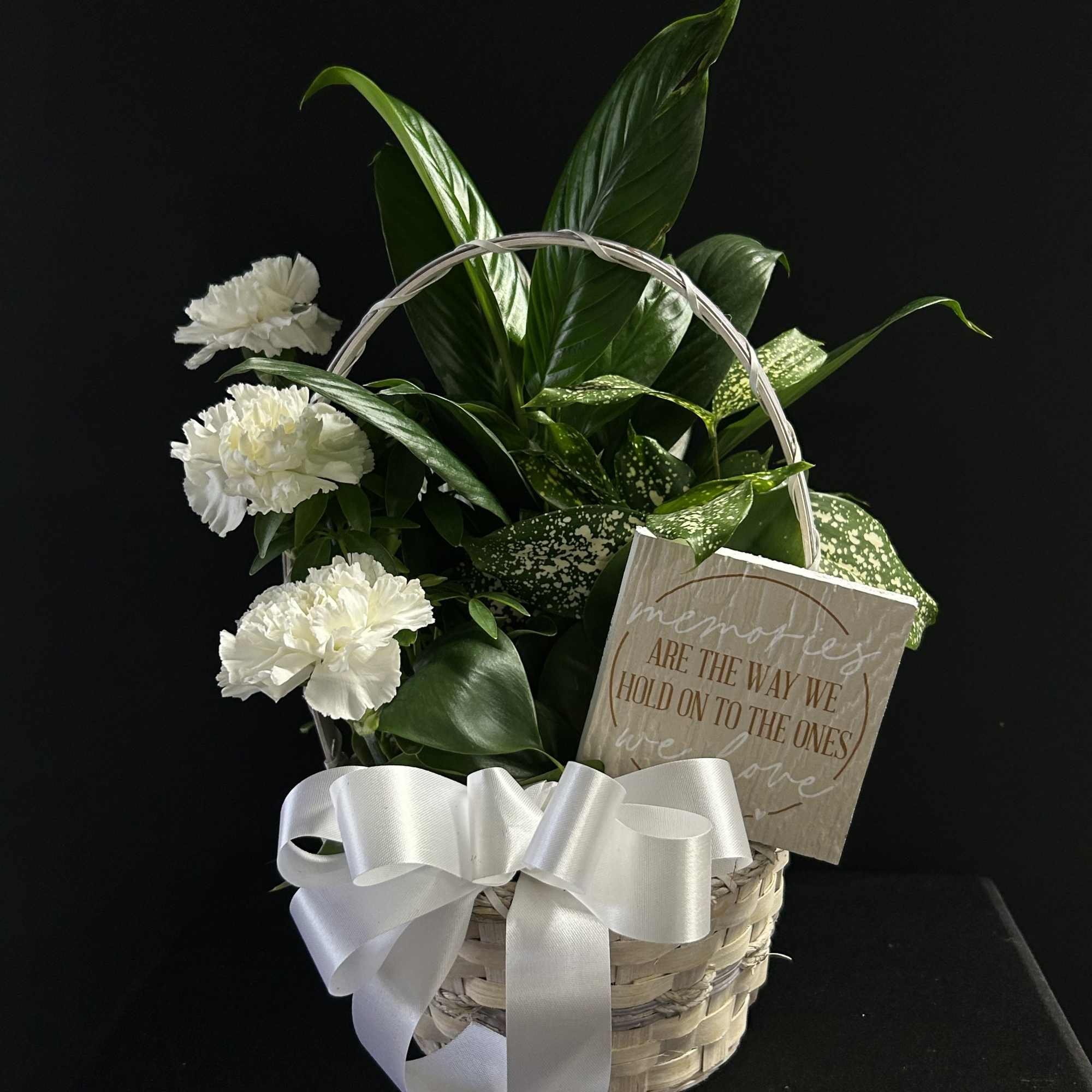 White carnations in a wicker basket with a white ribbon