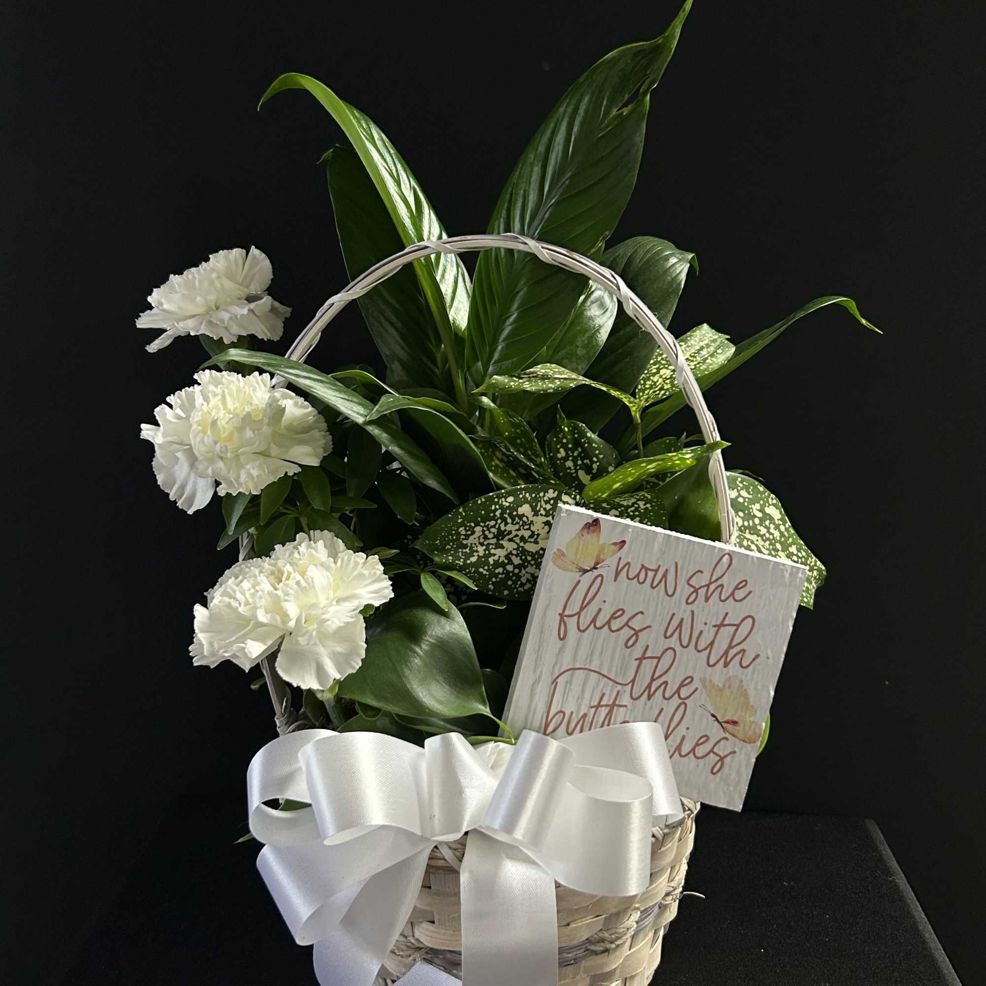 White carnations in a wicker basket with a ribbon and card