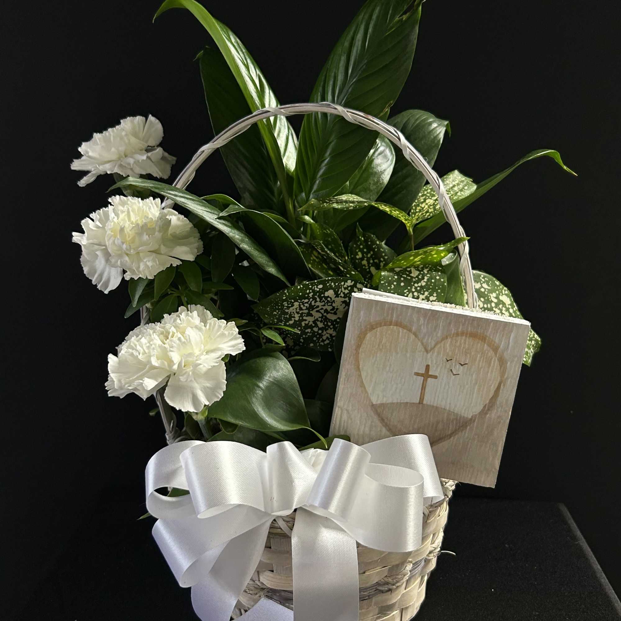 White carnations in a basket with a ribbon and sympathy card