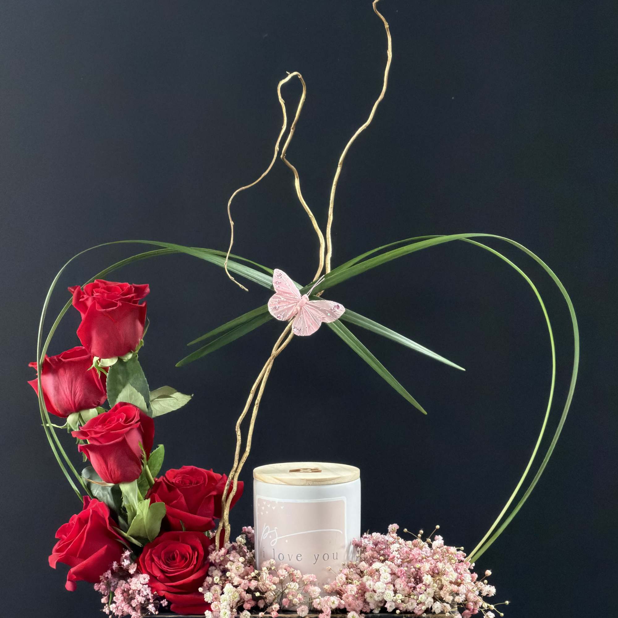 Red roses arranged with a candle in a heart-themed box