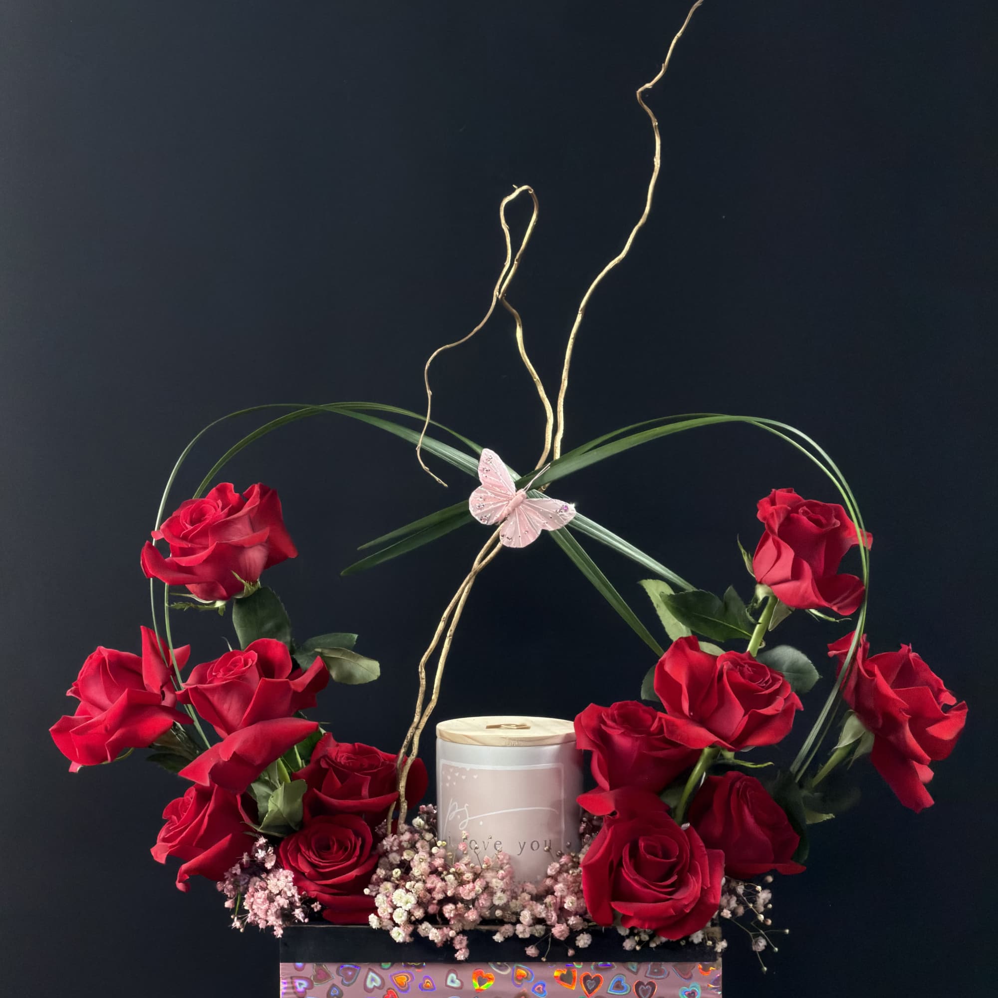Heart-shaped rose arrangement with a candle and butterfly accent