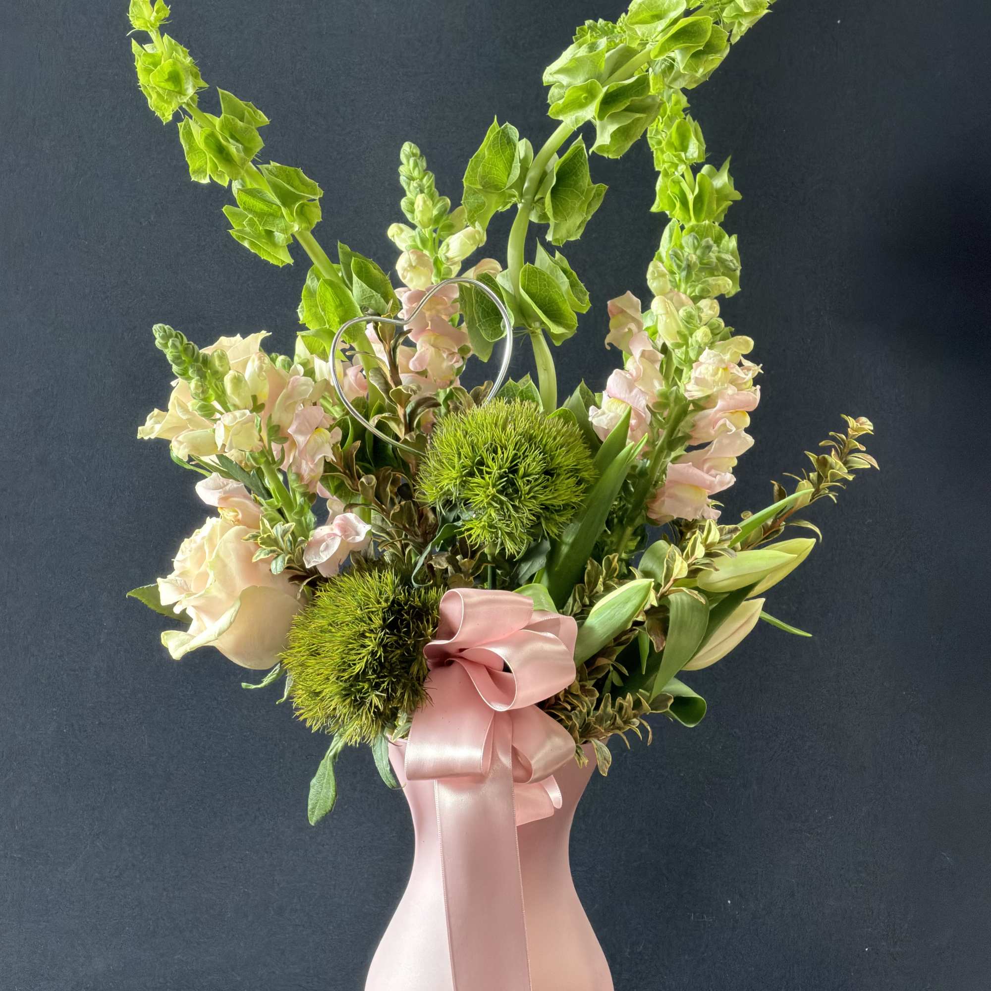 Pink vase arrangement with pale snapdragons and green blooms
