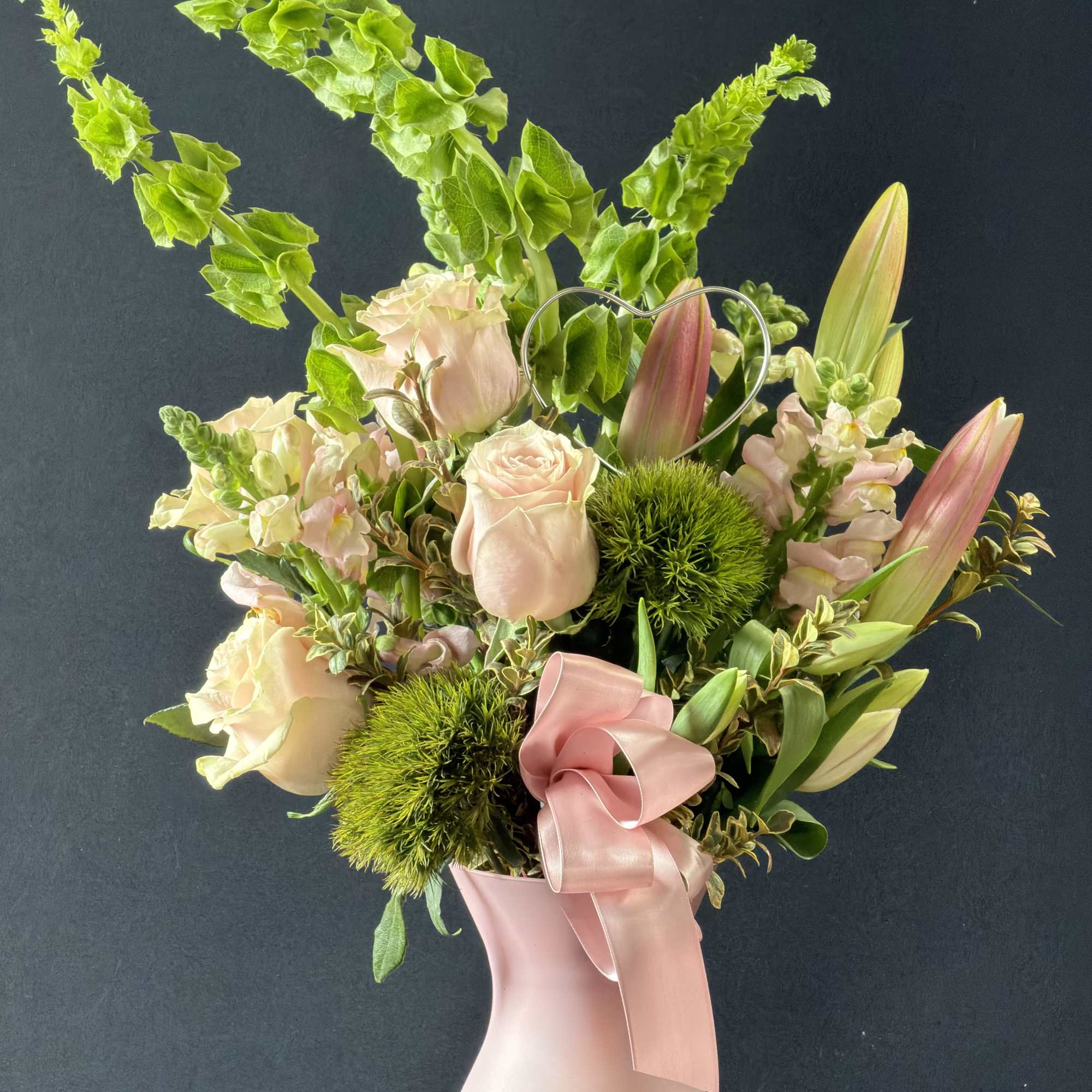 Pink roses and lilies in a blush vase with a ribbon