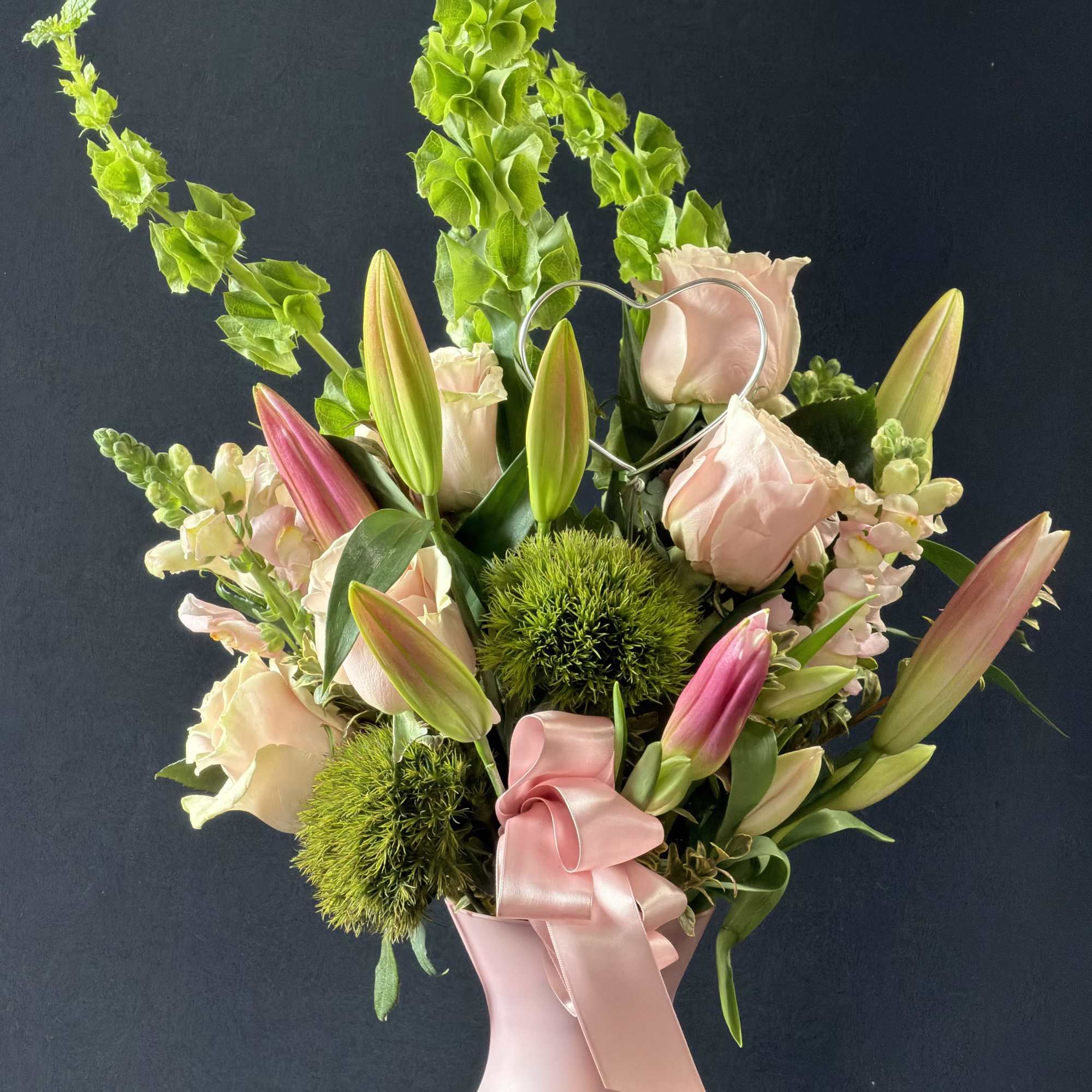 Pink roses and lilies in a blush vase with a satin ribbon