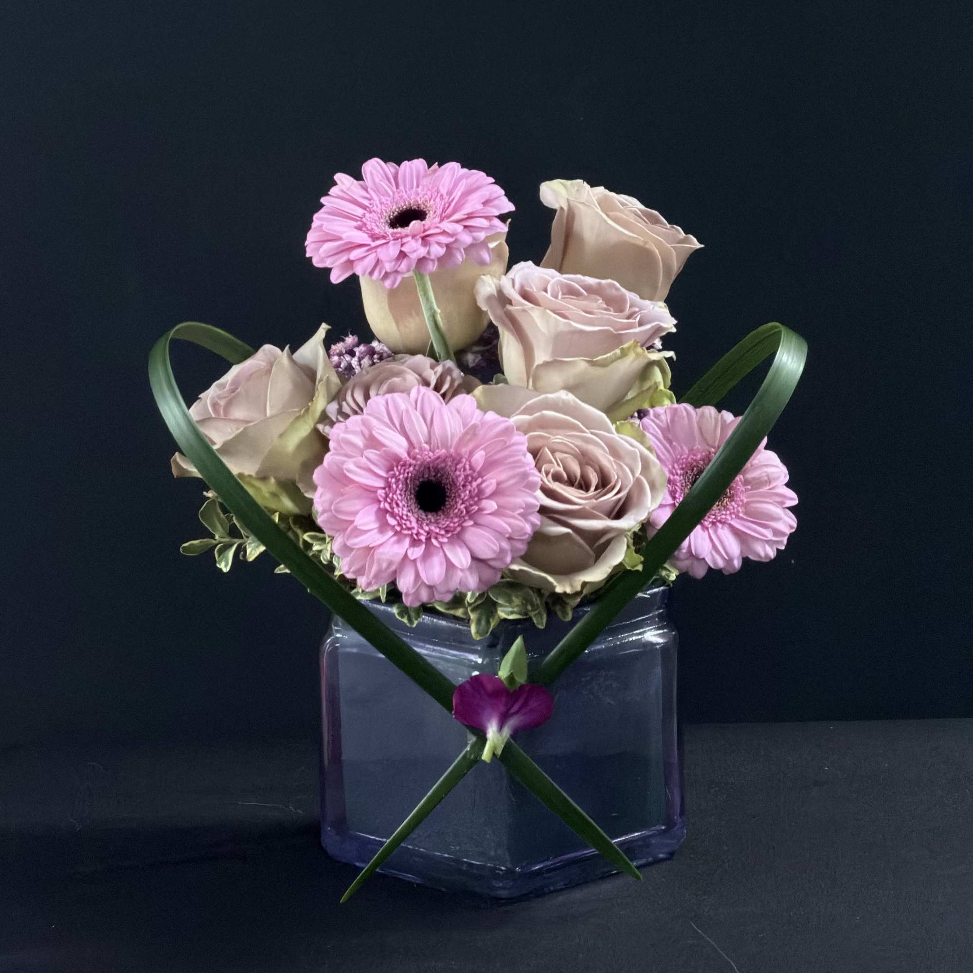 Pink gerbera daisies and pale roses in a square glass vase