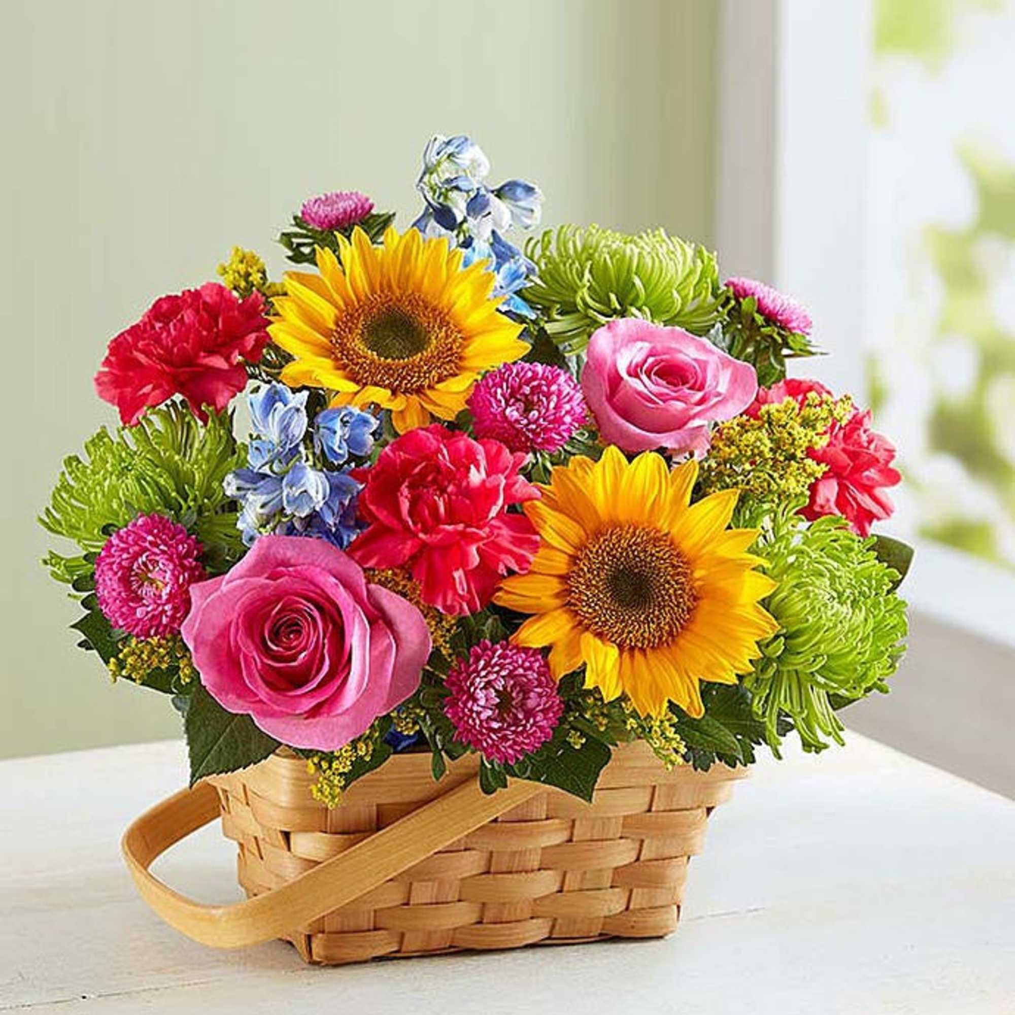 Basket arrangement with sunflowers, pink roses, and mixed blooms