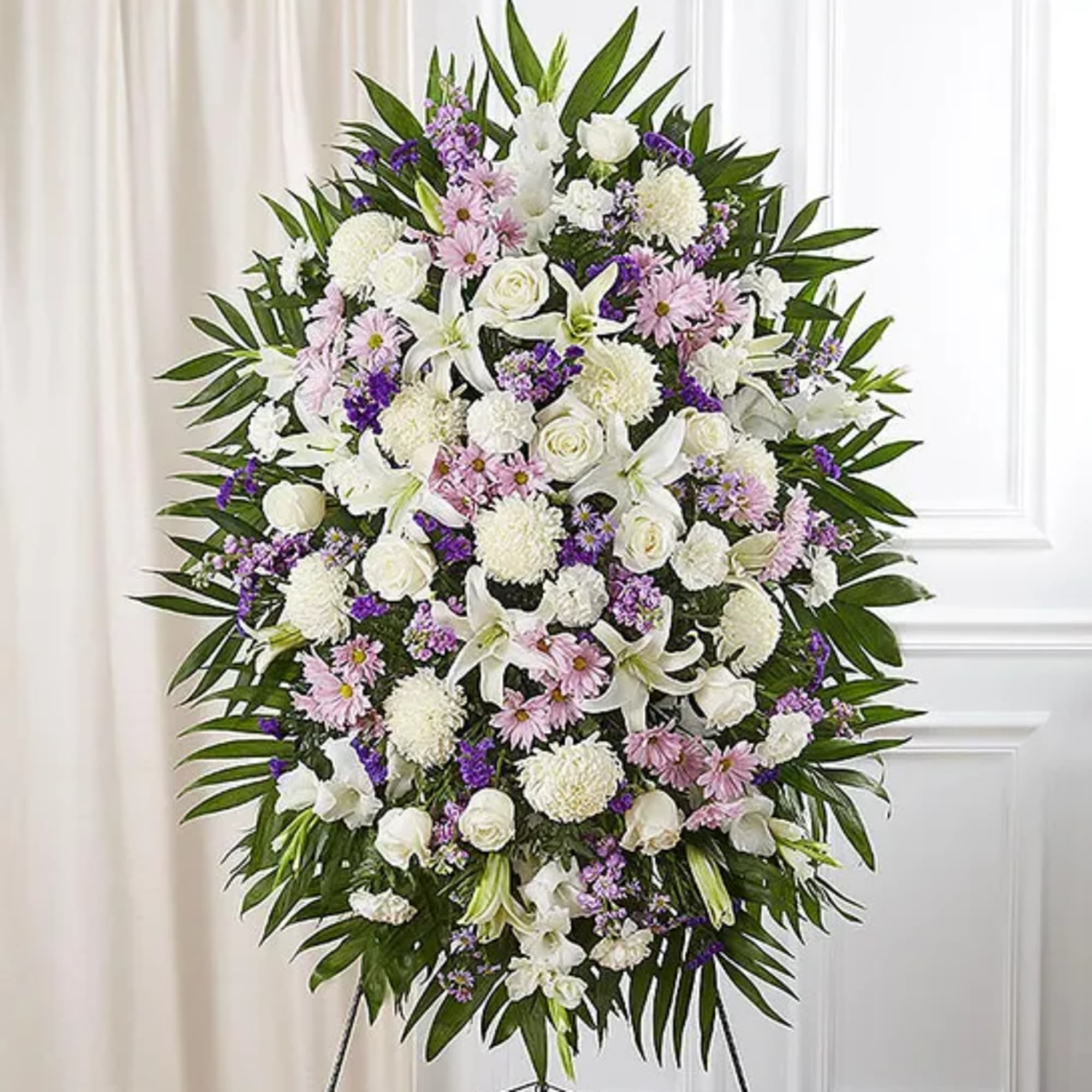 Standing funeral spray of white and lavender flowers on an easel