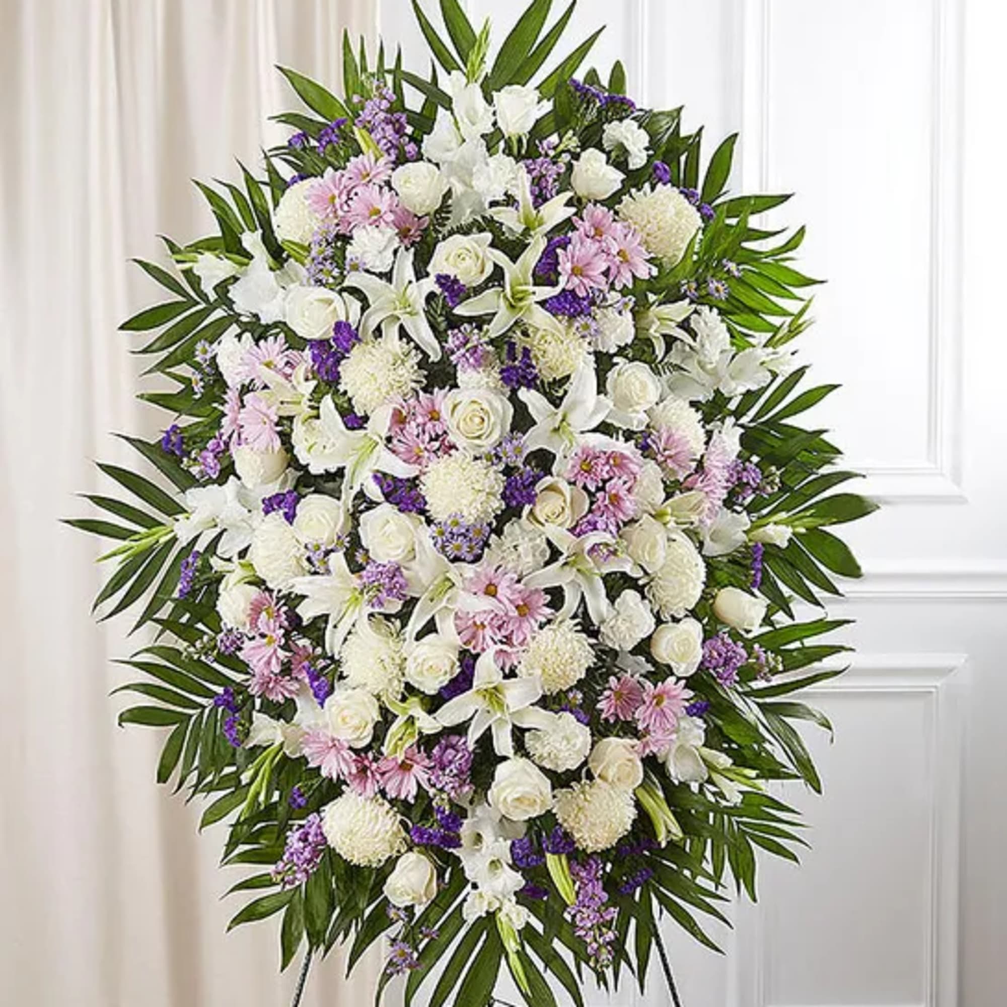 Standing funeral spray of white, pink, and purple flowers on an easel