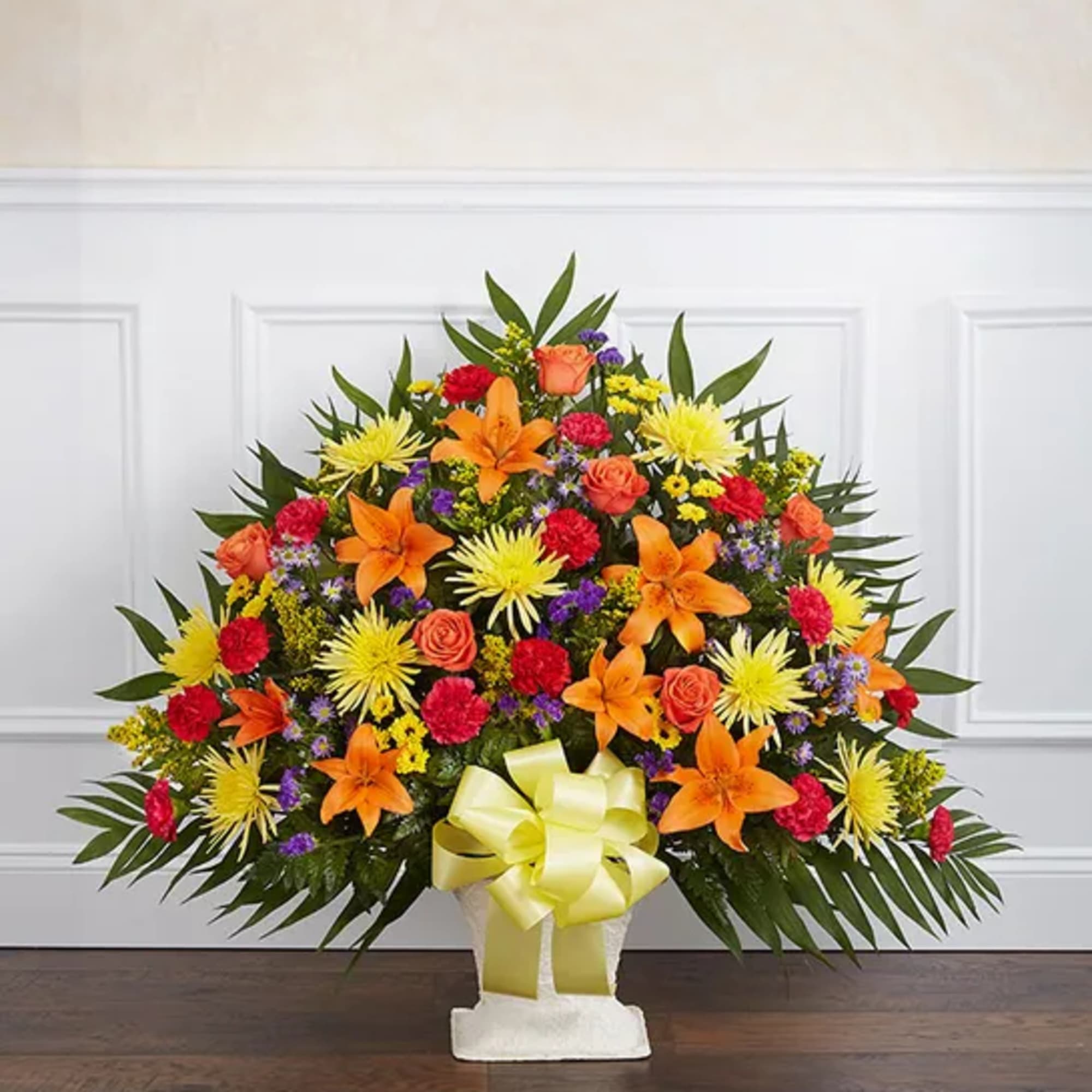 Large mixed floral arrangement with orange lilies and yellow daisies in a white vase