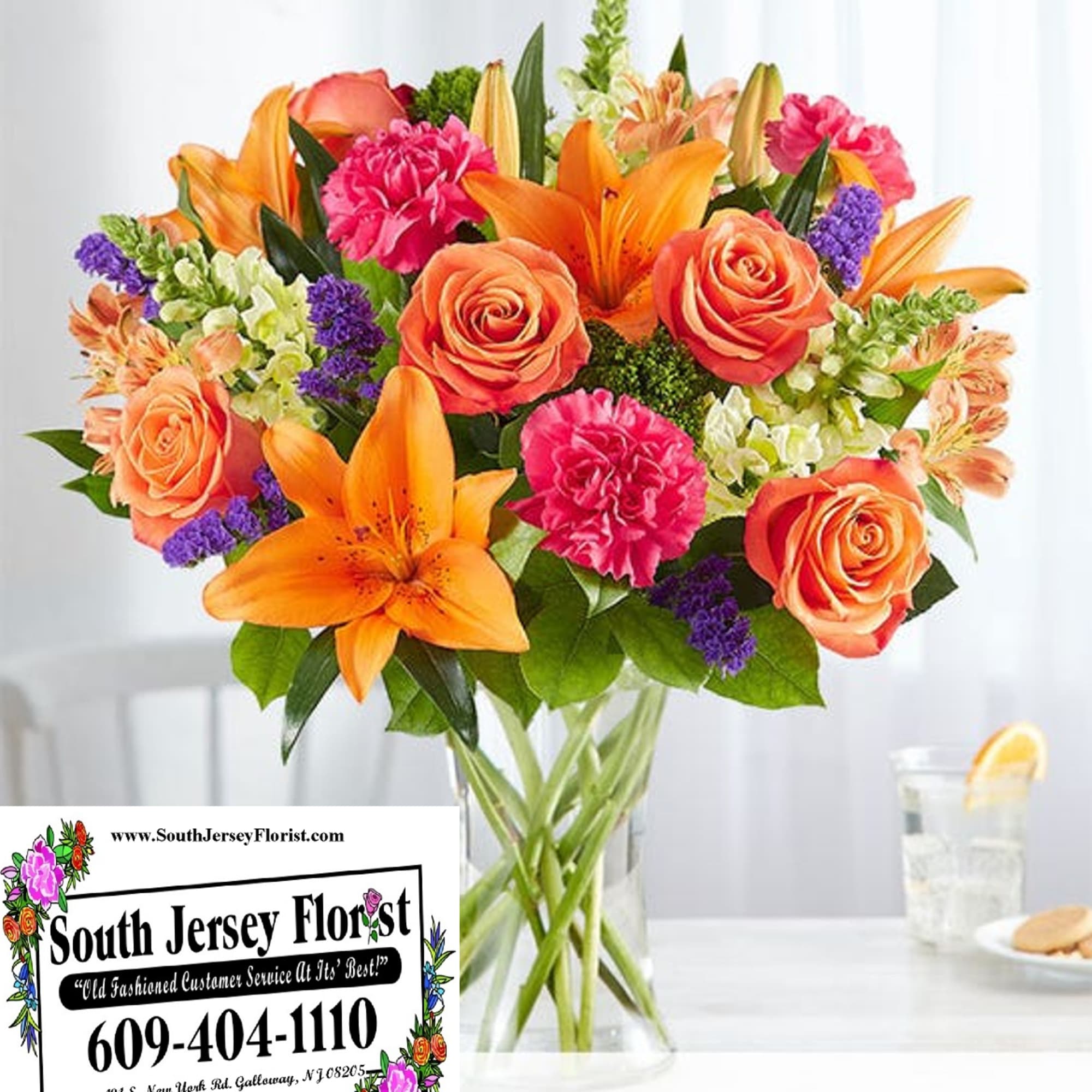 Bouquet of orange lilies, coral roses, and pink carnations in a glass vase
