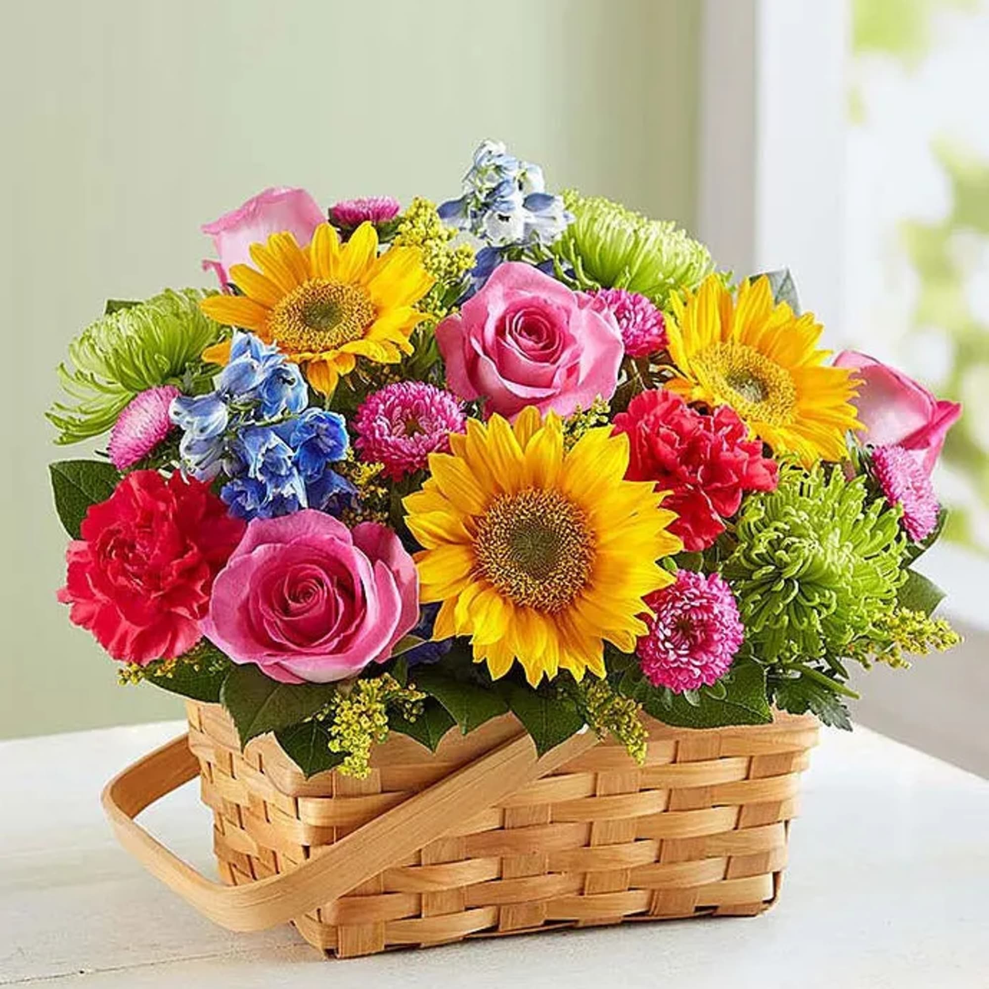 Mixed bouquet in a woven basket with sunflowers, roses, and chrysanthemums